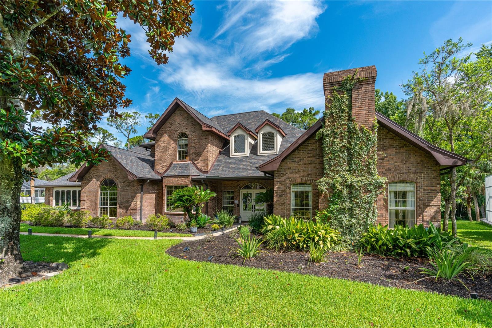 Virtually Staged. Situated on a sprawling over one-acre homesite, 73 Shadow Creek Ln in GATED Breakaway Trails offers the perfect combination of space, privacy, and luxury. This beautifully RENOVATED estate features an expansive floor plan with 5 spacious bedrooms, multiple flex spaces including a dedicated office & bonus room, 3+ car garage, 1.23 acre lot, NEW ROOF, and POOL & jacuzzi-making it ideal for large families, multi-generational living, or those who simply love having room to spread out. Thoughtfully updated throughout, this move-in-ready home showcases quality craftsmanship, designer finishes, abundant natural light, and exceptional indoor and outdoor living. A large front yard, extended driveway, mature landscaping, and stunning custom double glass front doors create outstanding curb appeal. Inside, the impressive foyer opens to soaring ceilings, skylights, and spacious living areas designed for entertaining. The spectacular two-story family room features luxury vinyl plank flooring, vaulted ceilings, a fireplace, skylights, custom draperies, and new Andersen sliding glass doors that seamlessly connect to the outdoor living space. The beautifully updated kitchen is the heart of the home, offering restored solid cherry oak cabinetry, premium Cambria quartz countertops with brass inlay, a center island with gas cooktop, Samsung Bespoke smart appliances, smart refrigerator, quartz sink, tile backsplash, crown molding, oversized walk-in pantry, and an abundance of cabinetry and storage. The adjoining dining room is surrounded by walls of glass overlooking the pool, creating an elegant setting for gatherings. The first floor also features a dedicated office with custom tile flooring, bay window, crown molding, and custom wood accent wall, along with a separate billiards room complete with built-ins, brick accent wall, and pocket doors. The oversized owner’s suite is a true retreat with luxury vinyl plank flooring, Andersen bay window, custom walk-in closet with built-ins, and a completely renovated spa-inspired bath featuring a walk-in tiled shower, freestanding jetted tub, dual quartz vanities. Upstairs offers three generously sized bedrooms, including one with a private en-suite bath and two connected by an updated Jack-and-Jill bath with dual sinks and walk-in tiled shower. A fifth bedroom over the garage provides incredible flexibility with a walk-in closet. Additional features include an updated powder bath, renovated pool bath with direct outdoor access, oversized laundry room with commercial sink, cabinetry, accessible attic storage, under-stair storage, back-entry 3+ car garage. Outdoor living with an oversized screened SALTWATER pool and spa, expansive tiled lanai. The deep wooded backyard creates an incredibly private setting rarely found in today’s market. Extensively updated improvements include a 2023 roof with 2 ply water barrier, 2 new HVAC systems with air purification, new insulation, new gutters, 3 new garage doors, LVP flooring, Samsung Bespoke appliances, new pool pump/cell/screens/child safety barriers. Located within the GATED community of Breakaway Trails, residents enjoy 24-hour gated security along with amenities including a clubhouse, community pool, tennis and pickleball courts, playground, walking trails, and beautifully maintained tree-lined streets. 73 Shadow Creek Ln presents an exceptional opportunity to own a beautifully renovated luxury estate in one of Ormond Beach’s most sought-after communities.