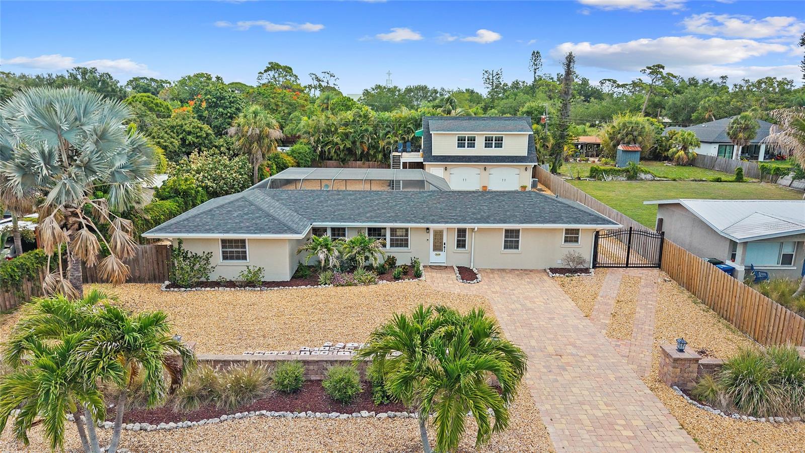 Offered below appraised value at $999,900, this truly one-of-a-kind Sarasota property presents a rare opportunity to own a private family compound just minutes from Siesta Key and located West of the Trail in the highly desirable Pine Shores neighborhood. Set on an oversized 0.34-acre gated, fenced, and walled homesite, this exceptional property offers two separate living residences, incredible flexibility, and resort-style outdoor living — all with NO HOA and NOT located in a flood zone.  This property also represents an outstanding investment opportunity with a proven rental history and strong income-producing potential, making it ideal for seasonal rentals, multigenerational living, guest accommodations, or long-term investment strategies. The beautifully maintained main residence features 3 bedrooms and 3 baths with approximately 1,685 square feet of living space and is being offered fully turnkey furnished. ROOF (3 - 4 years old), HVAC 2025, TANKLESS WATER HEATER 2025.  Pride of ownership is evident from the moment you arrive, with a long paver driveway leading to a charming, gated breezeway entrance and lush, low-maintenance tropical landscaping. The main home showcases polished terrazzo flooring, crown molding, remodeled kitchen and baths, granite countertops, impact-resistant windows and doors, and a state-of-the-art water filtration system. Outdoor living is exceptional with a heated saltwater pool, spa, summer kitchen, and expansive entertaining areas designed for the ultimate Florida lifestyle. Built in 2013, the detached oversized two-car garage structure adds tremendous value and versatility. Upstairs, guests or extended family will enjoy a spacious studio apartment complete with a full kitchen, breakfast bar, custom cabinetry, hardwood flooring, upgraded lighting and fans, built-in hideaway bed, full bath, and private laundry area. The garage also includes built-in storage shelving and an additional side carport. The oversized paver driveway and side access provide abundant room for boat, RV, or recreational vehicle parking. The expansive lot also offers future flexibility with room to potentially expand, add additional structures, or create a custom luxury estate environment. Located just minutes from Siesta Key Beach, Phillippi Estate Park, shopping, dining, and Sarasota’s vibrant cultural attractions, this is a truly special property combining location, privacy, flexibility, lifestyle, and investment value in one extraordinary offering.
