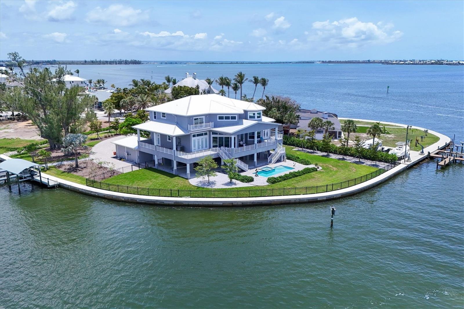 Compelling New Price!  Magnificent 5 bedroom, 5 bath waterfront estate with over 5,300 sq.ft. in the historic waterfront neighborhood of Cape Haze offers mesmerizing panoramic views in every direction and superb boating access. Built in 2021 the luxury home sits on maybe the most spectacular waterfront site in the area. The property is nearly a full acre and is surrounded by Pelican Bay and the Intracoastal Waterway with over 350 feet of seawall and excellent dockage opportunities. Permitting is in progress for twin 50' long docks for vessels with 14'10'' beams (attached site plan).  And endless other dock design variations are possible as well.  Less than a mile to the Gulf of Mexico and Charlotte Harbor, even bigger water is only minutes away. Drive down the long round-about driveway with stunning landscaping and towering mature trees, and gorgeous views of the bay and dockage before you park your car. Designed and built to highest coastal construction standards, the property is at home on the water. Heavy duty concrete piling and poured beam construction, impact storm windows and doors, metal roof and a 80KW Kohler generator with a 1,000 gallon propane tank. Entering the stunning home a grand 2 story great room with stunning beamed ceiling and a wall of 8 foot sliders and large transom windows that brings the serene activity of the Intracoastal into the home. The large chef's kitchen has a giant island, Wolf range, custom wood cabinetry with endless storage. Just off the kitchen is an enormous laundry / pantry room with a folding island, large windows and tremendous cabinet space. Incredible outdoor living areas with a massive lanai with wood paneled ceiling off the main living room, terraces off of bedrooms and a giant patio around the stunning heated pool and spa, all affording spectacular water views. Gorgeous primary suite with a generous bedroom, large walk-in closet, and a comfortable sitting space for looking out bay windows at the waterway. The spa-like primary bath offers a large soaking tub, pebble tile flooring, expansive roman shower and dual vanities. The guest baths all have their own unique designs with custom tile work and wood cabinetry vanities. In addition to 5 bedrooms there's a large office/den that also affords incredible water views. Incredible nature and wildlife with multiple bird nests on the property, and dolphin and manatees frequently swimming around the shore. Prime boating location being at the southern end of Cape Haze, you're in world-class fishing waters of Charlotte Harbor or off shore waters of the Gulf of America in no time. Just minutes to historic Boca Grande, lots of shopping and fine dining, numerous private golf clubs, the Coral Creek Jetport, and miles of tranquil sandy beaches.