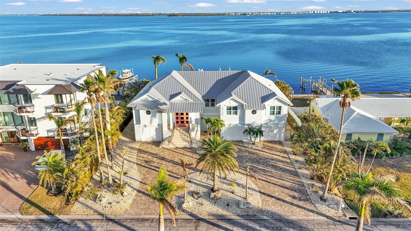 Truly A World of Its Own - Delightful Bay Front Living with sweeping views of the crystal clear waters of Anna Maria Sound and Tampa Bay.  This Elevated - One level, Custom built coastal residence is a tribute to aesthetic design, location and impeccable construction, finishes and taste.  Calm coastal colors and Shell stone Travertine flooring flow throughout the soaring living space featuring tongue and groove ceilings with solid wood beams, custom cabinetry with 100 year old pine accents, extensive millwork, custom handcrafted TV cabinetry, control 4 AV system, upgraded custom lighting and fans, an elevator, 8 foot solid core interior doors, a sound system, Plantation shutters and custom motorized window treatments and central vacuum.  The kitchen offers Thermador commercial appliances, a built-in pantry, and double laminated edge granite counters.  Bay views greet you from all angles and sliding doors lead to an elegant 63 foot balcony with outdoor kitchen and Trex stairs descending to the pool area.  3 of the 4 bedrooms are ensuite.  Ipe wood flooring flows throughout the bedrooms while travertine graces the bathroom floors.  Each of the bedrooms includes custom closet systems and Each of the 4 bathrooms includes Moen body wash and shower systems.  The exterior construction is top notch with a commercial grade 24 gauge standing seam metal roof, PGT impact windows and doors, second floor block construction with formed and poured concrete porches, Cantera door and icynene attic insulation.  The large garage space includes insulated garage doors and epoxy flooring.  This waterfront masterpiece opens to a charming Bayside freeform pool/spa, large travertine pool deck with plentiful seating/dining, and covered cabana.  For the boating enthusiast, this property is perfect with a Trex dock including water and electric and 28,000 and 10,000 boat lifts. This absolutely lovely home is decorator's masterpiece and a feast for the eyes.  Offered furnished less personal exceptions, this residence beckons those seeking a very special house and lifestyle.