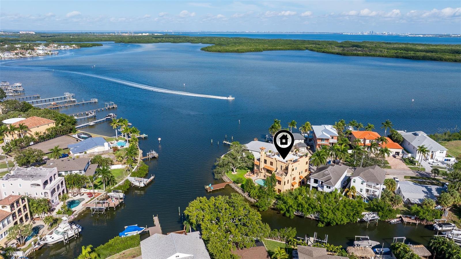 Under contract-accepting backup offers. Commanding a premier position at the point of Bayou Grande, this Mediterranean-inspired waterfront residence offers architectural presence, expansive water views, and exceptional construction. Built with solid block from ground floor to rooftop, the home delivers 4,456 square feet of heated living space and 7,155 total square feet, designed across multiple levels to maximize light, views, and functionality. A dramatic arched entry, custom carved wood doors, and a grand staircase with intricate iron detailing introduce the craftsmanship found throughout. Brazilian cherry floors, custom imported mahogany crown moldings, detailed trim, and soaring ceilings on the main living level and upper floors create an expansive and refined atmosphere. The main living areas showcase the setting with walls of high-end Pella hurricane windows and doors framing uninterrupted water views and filling the home with natural light, anchored by a marble gas fireplace. Multiple gathering spaces flow seamlessly, ideal for entertaining and everyday living. The kitchen is anchored by propane gas service and designed for both function and style, featuring extensive cabinetry, stone countertops, a large center island, Wolf appliances, a wine refrigerator, and separate refrigerator and freezer drawers. A mirrored bar area with built-in wine storage adds an additional layer of sophistication while remaining visually connected to the living areas and water views. Outdoor living is exceptional, featuring a resort-style pool alongside a brand new composite dock with electrical for a future boat lift and a thoughtfully designed seawall cutout that creates a natural ramp directly into the water for launching kayaks and paddleboards. A rear-facing garage allows effortless access, making it easy to carry water toys straight from the garage into the bay. The point lot provides wide open Tampa Bay views, calm protected water frontage, and enhanced privacy. The upper levels offer a well planned bedroom layout with excellent separation. The primary suite captures panoramic water views and features a large custom walk-in closet and a spa-like bathroom with custom cabinetry, a separate Jacuzzi tub, and a spacious glass-enclosed steam shower. Guest suites are generously sized and well appointed, including high-end finishes such as heated bathroom floors. A private elevator provides seamless access from the ground level garages to the expansive rooftop terrace. Plumbed for an outdoor kitchen with gas, the rooftop offers sweeping views across Tampa Bay and surrounding waterways, creating an ideal setting for entertaining or quiet evenings. Additional features include a 6+ car garage with space for vehicles, water toys, and golf carts. A separate tiled and finished portion of the garage offers flexible use as a poolside retreat, gym, recreation space, or overflow entertaining area. Abundant storage, a 2020 roof, solid block construction, a two-zone HVAC system, and a natural gas water heater complete the home. Located in one of NE St Pete's true waterfront neighborhoods directly on Tampa Bay, residents enjoy easy access to Islander Market, A-rated Shore Acres Elementary, waterfront parks, and local dining and shopping. The location allows travel by bike, golf cart, or boat to downtown St. Pete. With no bridges to the Gulf of Mexico, this is an exceptional boating location offering world-class fishing and water access. This home delivers refined design and a true Tampa Bay lifestyle.