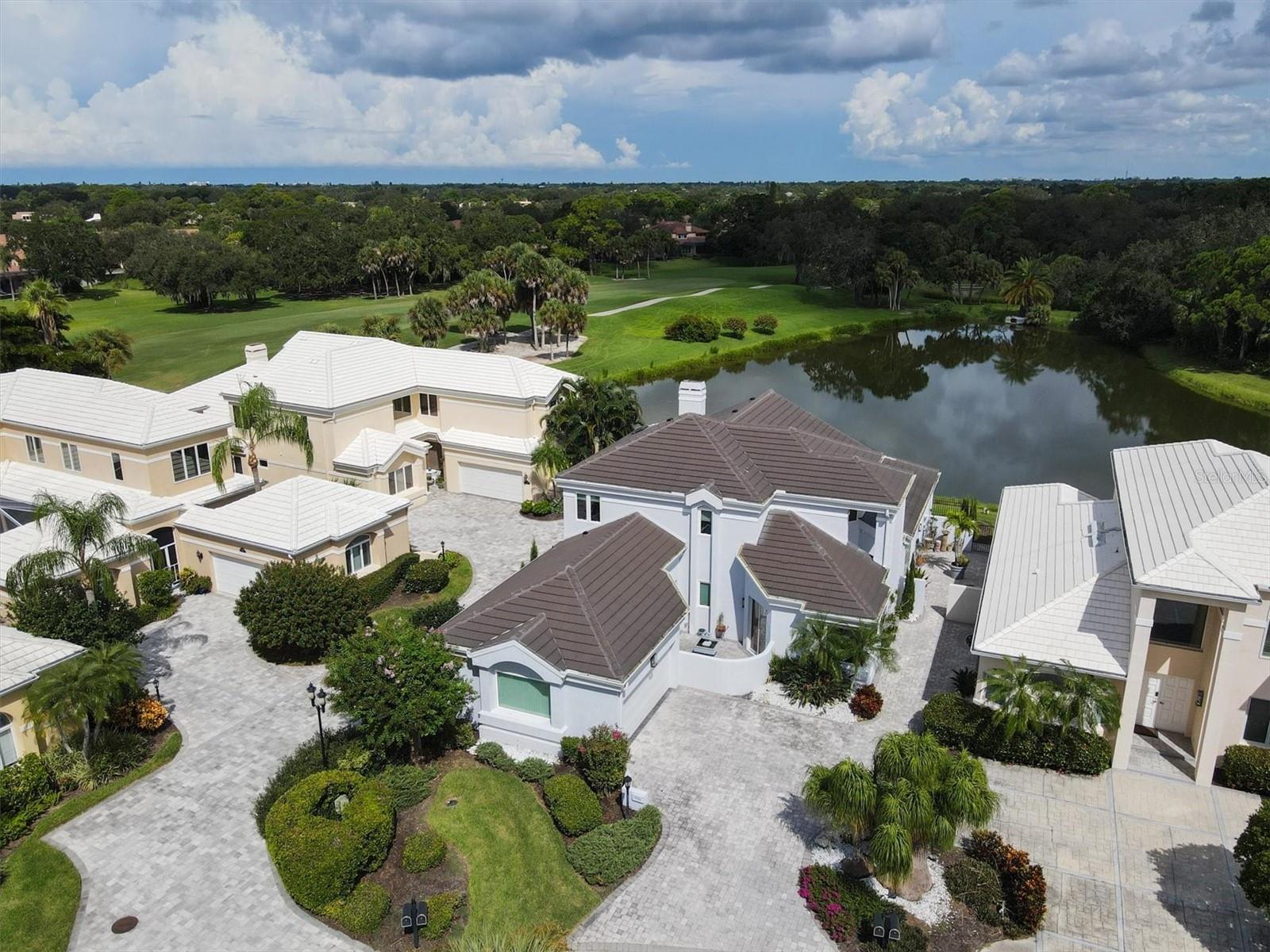 Positioned along the tenth fairway within the gates of the highly coveted Prestancia Golf & Country Club, this exceptional contemporary residence offers a rare opportunity to embrace refined luxury and elite golf course living. Architectural drama unfolds through soaring vaulted ceilings, a grand cherry and mahogany staircase, custom Wenge wood accents, and curated marble and granite finishes, all illuminated by bespoke designer lighting that elevates the home’s elegant interior.

At the heart of the home, the gourmet kitchen is thoughtfully designed to cater to both everyday elegance and upscale entertaining. Overlooking a tranquil fountain and private courtyard, the space seamlessly connects indoor and outdoor living. Premium stone countertops, custom cabinetry, a Wolf gas range with double ovens and warming tray, a Grohe faucet, and a Fisher & Paykel dishwasher underscore the kitchen’s exceptional quality. Generous counter seating invites casual gatherings, while the adjacent walk-in catering room—currently styled as an elevated coffee bar with sink—adds a layer of convenience befitting luxury living.

The main living area is anchored by a dramatic 20-foot Jerusalem stone feature wall enveloping an electric fireplace, creating an atmosphere of warmth and architectural distinction. Floor-to-ceiling views of shimmering water features and manicured fairways provide a constant reminder of the home’s coveted golf course setting.

The primary suite serves as a private sanctuary, offering direct access to both the patio and a secluded courtyard retreat. The spa-inspired ensuite bath is designed for indulgence, featuring a deep soaking tub, walk-in shower with full-body system, dual vanities, a bidet, and a custom walk-in closet that balances elegance with functionality.

Guest accommodations are equally refined, with multiple en-suite bedrooms providing privacy and comfort. A flexible first-floor bonus room offers the ideal space for a private office or additional guest suite. Upstairs, guests may enjoy a secluded bedroom and bath, complemented by a gorgeous bonus lounge overlooking the main living area perfect for movie nights or entertaining, complete with a wet bar for evening cocktails.

Meticulously maintained, this residence is ideally located moments from Sarasota’s world-class dining, luxury shopping, and cultural attractions. Prestancia offers a premier country club lifestyle. Optional membership to TPC Prestancia Golf, Social and Sport provides championship golf.  The association provides community pool conveniently located across the street.  All these exclusive benefits make this home an exceptional offering for those seeking prestige, privacy, and an elevated club-centric way of life.
