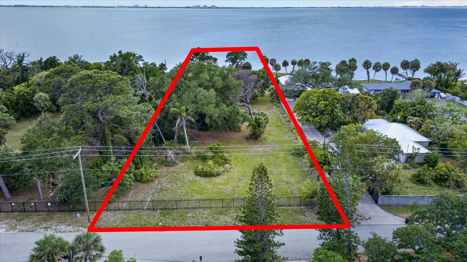 Discover a once-in-a-lifetime opportunity to own a PREMIER 1.08-ACRE BAYFRONT LOT located “WEST OF THE TRAIL” at 8258 Long Bay Blvd., Sarasota, FL — a true TROPHY PROPERTY offering UNOBSTRUCTED VIEWS OF SARASOTA BAY, priceless SUNRISES & SUNSETS, and endless possibilities to build your CUSTOM LUXURY ESTATE! This OVER 1 ACRE WATERFRONT LOT features UTILITIES AVAILABLE, a NEWER SEA WALL already in place, NO HOA FEES, and is positioned at a HIGH ELEVATION where the MAJORITY OF THE PROPERTY IS NOT LOCATED IN A FLOOD ZONE — ABSOLUTELY UNHEARD OF for BAYFRONT living! SAVE THOUSANDS IN CONSTRUCTION COSTS by building outside of the A & V flood zones while enjoying peace of mind and the ultimate Florida waterfront lifestyle. This MUST-SEE VACANT LOT wraps around the BAY with exceptional DEPTH, PRIVACY, and room to BUILD A DOCK large enough for YACHTS, BOATS, JET SKIS, KAYAKS, PADDLEBOARDS, and all your WATER TOYS. Spend your days FISHING RIGHT FROM YOUR BACKYARD, boating across Sarasota Bay, entertaining waterfront guests, or simply relaxing while taking in breathtaking water views every morning. The iconic CROSLEY MANSION and world-renowned RINGLING MUSEUM are your neighbors to the south, placing you in one of Sarasota’s most PRESTIGIOUS and CULTURALLY RICH waterfront corridors. This PRIME INVESTMENT OPPORTUNITY also allows for an ACCESSORY DWELLING UNIT (ADU) up to 80% of the primary home size — ideal for a PRIVATE GUEST RETREAT, MULTI-GENERATIONAL LIVING, or INCOME-PRODUCING RENTAL with its own address. Enjoy DEEP BAYFRONT TRANQUILITY while remaining minutes from WORLD-CLASS DINING, SHOPPING, ARTS, ENTERTAINMENT, and Sarasota’s stunning GULF BEACHES. OWNER IS MOTIVATED — opportunities like this rarely hit the market, so CONTACT US TODAY before this extraordinary piece of SARASOTA BAY PARADISE is gone!
