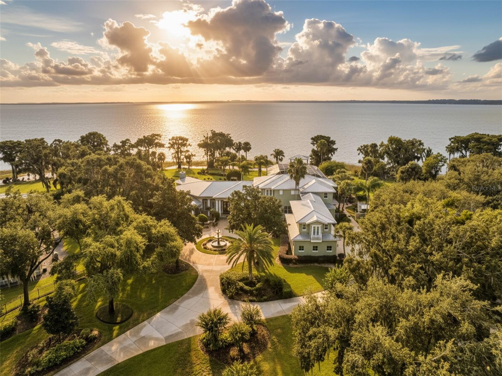 Experience a rare blend of serenity, sophistication, and lakefront living on the pristine shores of Lake Harris, part of Central Florida’s famed Harris Chain of Lakes. Tucked behind a private gated drive, this extraordinary property spans 3.06 acres with the added benefit of 46± acres of protected conservation land, creating a sense of unrivaled privacy and natural beauty.
Inside the 8,596-square-foot custom residence, craftsmanship takes center stage. Walls of windows capture shimmering water views from nearly every room, while rich design details, from diagonal-laid hardwood floors and porcelain tile to tongue-and-groove, barrel, coffered, and tray ceilings, set an elegant tone. Handcrafted millwork, a stunning leaded glass entry, granite surfaces, multiple fireplaces, and upscale finishes add warmth and timeless appeal.
The home was designed for both quiet moments and unforgettable gatherings. An open chef’s kitchen flows into welcoming dining and living areas, perfect for entertaining. Additional spaces include a first-floor game room with its own chilled wine room, a private office with custom woodwork, a dedicated homework station, and a versatile bonus room over the garage, ideal for a theater, guest suite, fitness area, or creative retreat. Each bedroom features a private ensuite bath, offering comfort and privacy for family and guests alike.
Step outside to an outdoor haven where you can wander a serene path to a lakeside firepit, relax by the pool, or enjoy your private boathouse with dual lifts for effortless days on the water. The expansive, beautifully landscaped grounds have even hosted picturesque weddings, making this estate as enchanting for events as it is for everyday living.
All this tranquility comes with surprising convenience. You’re moments from charming downtown Leesburg and Mount Dora, with nearby golf, shopping, dining, and healthcare options such as UF Health and AdventHealth. Leesburg International Airport is close at hand, while Disney and Orlando International Airport are less than an hour away.
This is more than a home, it’s a private lakeside retreat designed for refined living, effortless entertaining, and unforgettable memories.