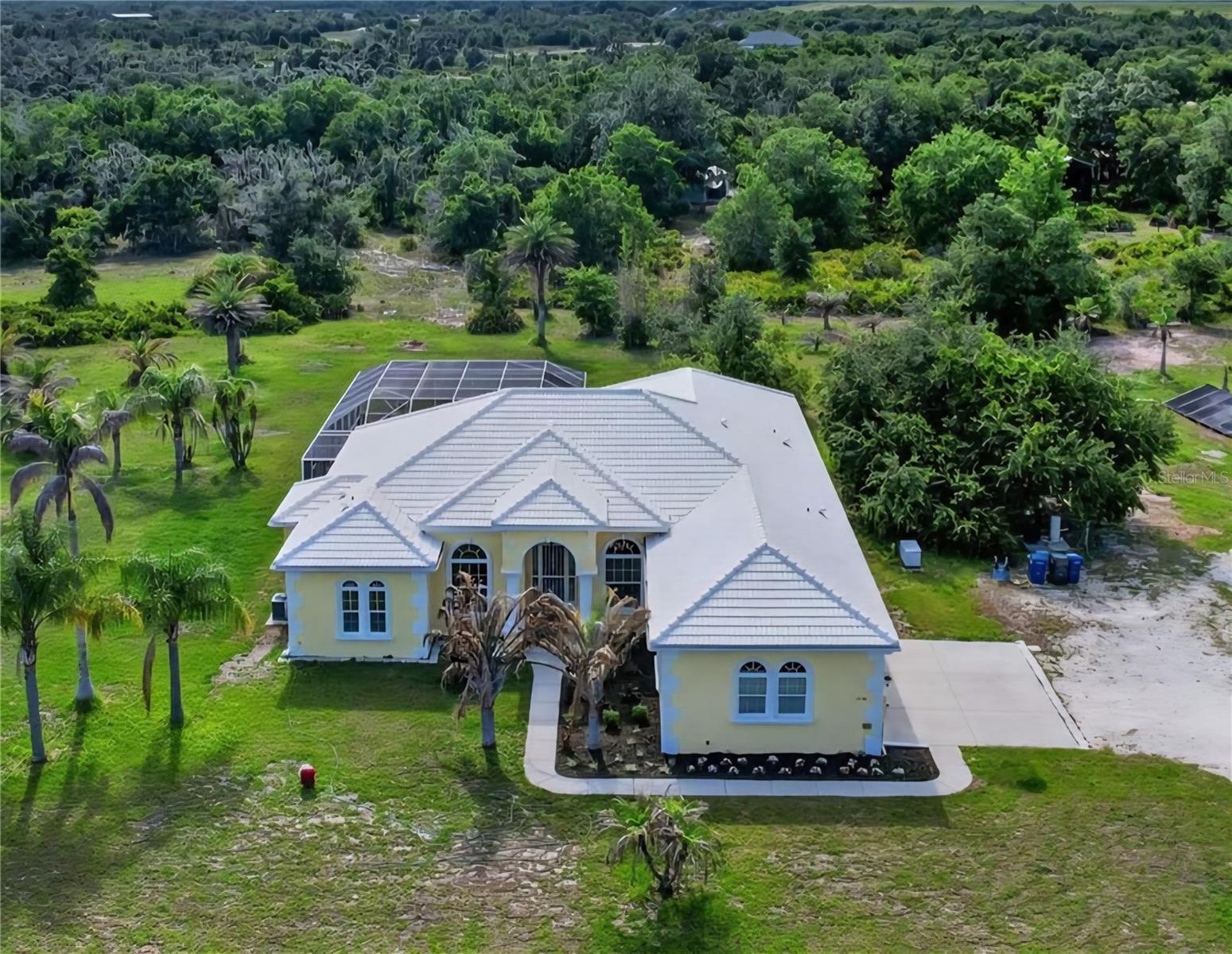 Welcome to a different kind of Florida living — where wide-open skies, room to roam, and luxury comforts all come together on nearly 6 fenced acres in Myakka City. Behind the private coded motorized entry gate, you’ll find a custom-built Mark Cahill home designed for both everyday comfort and the kind of lifestyle people move to the country to enjoy. Whether you’re bringing horses, outdoor toys, or simply looking for more privacy and freedom, this property gives you the space to live the way you want.

Inside, soaring 14-foot ceilings, 8-foot doors, crown molding with accent lighting, and a double tray ceiling create an impressive yet comfortable atmosphere. The living room features built-in shelving and flows toward an aquarium window overlooking the pool, giving you peaceful, unobstructed backyard views from the kitchen nook and main living areas. Gorgeous chandeliers elevate both the formal dining room and kitchen, while all-tile flooring throughout means no carpet anywhere in the home. The flexible floor plan offers 4 bedrooms, 3 baths, formal dining, formal living room, a dedicated office and oversized kitchen with breakfast bar & island.

Step outside and you’ll understand what makes this property special. The saltwater pool features PebbleTec coating, solar heat, and a resistance swim system that allows you to swim against the current for exercise and training right from home. Additional features include a winter safety cover, cool deck surfacing, retractable motorized awning, sunshade, pool bath access and an outdoor shower nearby. You can relax in privacy while enjoying the peaceful surroundings that make country living so appealing.

For buyers needing space for hobbies, equipment, recreational vehicles, or business use, the 900 sq ft workshop is a standout feature with water, power, and approximately half the space under air conditioning. Attached covered parking provides additional room for boats, trailers, or equipment, while the home itself includes a 3-car garage. Nearby recreational opportunities include equestrian trails, boating areas, parks, bow hunting, and a nearby motorsports facility for those who enjoy the active outdoor lifestyle.

This home was built with long-term durability and efficiency in mind, including hurricane-impact windows and garage doors, Icynene insulation for energy efficiency, a Generac generator with buried 250-gallon propane tank, security system with sensors on all doors and windows, and a brand new (2026) $30,000 well system with sulfur filtration and chlorinated pipes for clean drinking water. The barrel tile roof adds timeless curb appeal, while the property has had no flooding and no hurricane damage. An owned 9.5 kW grid-tied solar energy system positioned on the property conveys with the home and helps keep energy costs remarkably low — with no lease to assume.

The community itself offers an equestrian park, riding opportunities, picnic areas near the lake, planned events, and a low HOA fee of just $800 per year. If you’ve been searching for a property where you can spread out, enjoy nature, entertain friends, keep horses, store your toys, and still enjoy upscale finishes and amenities, this is exactly what you’ve been waiting for. Schedule your private showing today and come experience the space, privacy, and lifestyle this exceptional property has to offer!
