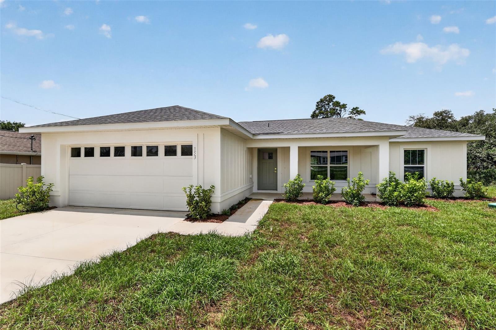 Experience Modern Elegance and Privacy in a beautiful natural setting. Welcome to your dream home in beautiful Ocala, Florida, where superior craftsmanship meets exceptional value. This stunning residence sits on an expansive lot of over a quarter acre and backs up to a greenspace with no rear neighbors. From the moment you arrive, the curb appeal is evident. The exterior showcases stylish board and batten Hardie Board siding, an elegant upgraded front door, and a charming 119-square-foot front porch that invites you to sit and relax. Inside, the home opens into a bright and airy open-concept layout featuring luxurious vinyl plank flooring that stretches throughout every room for a seamless, modern feel. The kitchen is a true chef’s delight, meticulously designed with sleek stainless-steel appliances, a chic tiled backsplash, and upgraded counters. Elegant pendant lights hang over the central island, creating the perfect atmosphere for casual meals or your morning coffee. Your private retreat awaits in the spacious master suite, which features a decorative tray ceiling and a spa-like en-suite bathroom boasting a beautifully tiled shower. Every detail has been considered for your comfort, including ceiling fans in all three bedrooms. The living space extends outdoors to a 128-square-foot screened-in lanai equipped with its own ceiling fan, overlooking large backyard. Location is convenient to Ocala, Belleview, Lake Weir and The Villages.