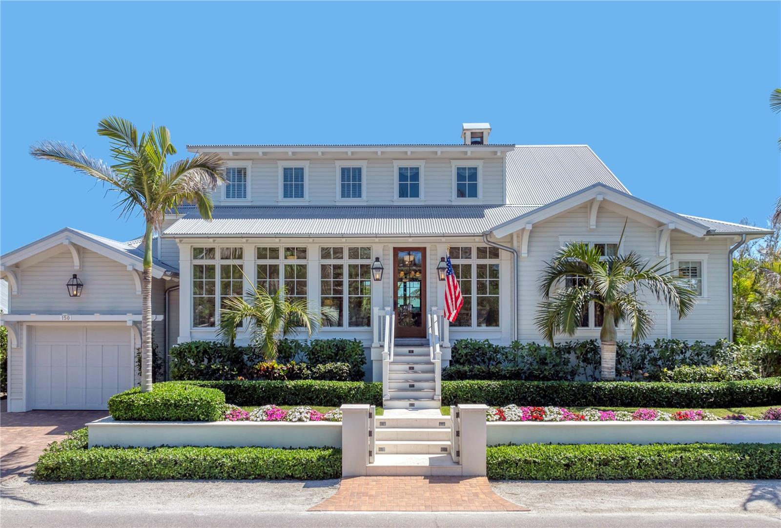Located in the heart of the Village within the historic charm of Boca Grande, this exceptional 6-bedroom, 6-bath coastal retreat artfully blends timeless architecture with modern craftsmanship. Designed by Stofft Cooney Architects and built in 2020 by the island’s premier builder, Safety Harbor Construction, the residence offers over 3,800 square feet under air, including two beautifully appointed sunrooms, and was thoughtfully conceived for refined entertaining and seamless indoor–outdoor living. A custom mahogany front door opens to a classic “Gasparilla Inn” inspired sun porch with green high-gloss painted wood floors, introducing interiors rich with antique wormy chestnut reclaimed flooring, tongue-and-groove ceilings with decorative beams, and a striking Isokern Magnum wood-burning fireplace. The open-concept kitchen is a chef’s showpiece, appointed with leathered Taj Mahal quartzite countertops, dual dishwashers, WOLF and Monogram appliances, and a fully equipped butler’s pantry with ice maker, beverage drawers, wine refrigerator, and generous storage. A beautifully integrated dry bar in the living area features a copper countertop, additional beverage drawers, and an ice maker. British-inspired Origin bi-fold aluminum doors fully recess to transform the living space into an open-air sanctuary, complemented by a remote-controlled screen at the touch of a button. The outdoor kitchen is anchored by a custom built-in Kalamazoo Gourmet Fire Grill, designed to cook with wood, charcoal, or gas, with additional space for preferred appliances. The main-level primary suite captures serene outdoor views and features a private, spa-like bath with dual vanities, walk-in closet, and a full-size laundry room. Two additional guest suites complete the main level, including one reimagined as a den inspired by BZ’s Lounge at the iconic Gasparilla Inn. Upstairs, a cozy TV room provides an inviting setting for movie nights and game time. Three additional guest suites include one transformed into a bright craft room with charming views of Palm Avenue, along with a convenient second-floor laundry closet. Set on 81 feet of deepwater canal frontage with direct, no-bridge access to the Harbor and Gulf, the property is a boater’s dream. The private dock features over 600 square feet of Azek decking, a 20,000-pound boat lift (2020), and a 10,000-pound lift added in 2023. The main living level is elevated over 11 feet and constructed on a solid concrete base for peace of mind. A residential elevator services all floors from the extended one-car garage with golf cart side entry and additional storage. Andersen impact windows, Boral exterior siding, a corrugated metal roof, solid wood soffits, and a whole-home Reme Halo air purifier complete this impeccably built residence, offering the rare union of Village character, architectural integrity, and exceptional boating and beach access.