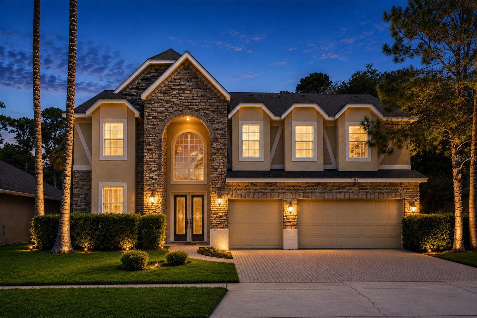 One or more photo(s) has been virtually staged. The moment you arrive, this impressive five-bedroom two-story pool home invites you in with a striking stone-accented exterior, mature landscaping, and a spacious three-car garage. Inside, soaring ceilings, dramatic windows, arched entryways, and beautiful wood flooring create an immediate sense of space, warmth, and possibility. Designed for both everyday living and memorable entertaining, the home offers multiple living and dining areas filled with natural light. The formal spaces feel open and elegant, while the family room features a stone fireplace, built-in niches, and seamless connection to the kitchen and outdoor living area. The fifth bedroom has been thoughtfully converted into a dedicated office with custom built-ins, creating an ideal work-from-home space, study, or private retreat, and can be easily converted back to a bedroom if desired. The kitchen is the heart of the home, featuring rich wood cabinetry, expansive counter space, a large center island, breakfast bar seating, tiled backsplash, recessed lighting, skylights, and an open layout that keeps everyone connected. Whether hosting friends, preparing meals, or enjoying quiet mornings, this space makes daily living feel effortless. The primary suite offers a comfortable retreat with generous space, natural light, and an ensuite bath featuring dual vanities, a soaking tub, and separate glass-enclosed shower. Additional bedrooms are spacious and flexible, with vaulted ceilings, ceiling fans, large windows, and neutral finishes ready for your personal style. The bathrooms offer practical layouts with generous vanity space and tub/shower combinations for family or guests. Step outside and discover the kind of Florida lifestyle buyers dream about. The screened pool and spa area features a paver patio, covered lanai, rock accents, water features, and a peaceful backdrop of mature trees and lush greenery. It is easy to imagine weekend gatherings, relaxing evenings, and quiet mornings by the water. Additional highlights include a dramatic two-story foyer, formal living and dining rooms, upstairs landing, custom built-ins, crown molding, recessed lighting, ceiling fans, decorative windows, abundant natural light, generous storage, and a large driveway with three-car garage parking. The community adds even more to enjoy, with scenic pond views, green space, playground, and a resort-style pool area. Conveniently located near shopping, dining, schools, parks, and major roadways, this home offers space, comfort, privacy, and lifestyle in one exceptional setting. Once you walk through it, you can feel how easily this home could become the one.