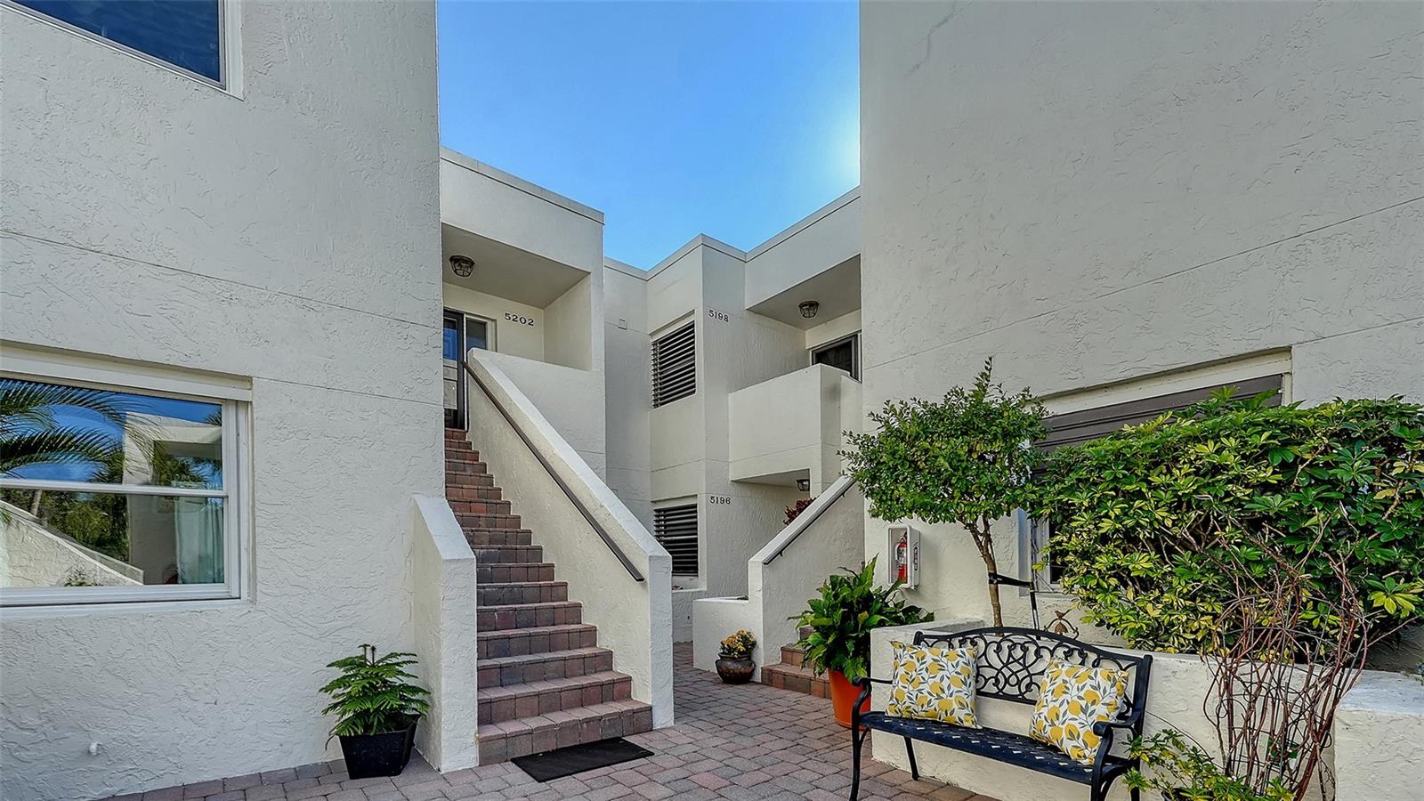 This beautifully reimagined first floor end-unit condominium in The Meadows offers serene lake and golf course views and a thoughtfully designed layout that lives like a private retreat. With two bedrooms, a den, and a carport, the residence is filled with natural light and enhanced by multiple outdoor spaces, including a screened lanai overlooking open vistas, a charming courtyard ideal for gardening or pets, and a paver patio accessible from the primary suite. The interior has been fully renovated with a clean, modern aesthetic and exceptional attention to detail. Cool, smooth crushed-shell flooring runs throughout, complemented by custom cabinetry, white quartz countertops, under-mount sinks with touch-activated faucets, and a suite of stainless steel appliances, including an induction/convection range. Subtle luxury touches such as re-surfaced smooth ceiling texture, recessed lighting, electronic shades, and dimmer switches add both comfort and convenience. Both bathrooms are finished to spa standards, featuring elegant European-style design, a rain shower, and refined fixtures. The primary bedroom is bright and welcoming, with a generously sized walk-in closet. The kitchen is supported by an oversized walk-in pantry that also houses a stackable front-load washer and dryer and the water heater. Major system updates include a full repipe in 2014, water heater in 2014, air conditioning in 2020, and new community roofs completed in 2022. The Heronmere condo community has its own pool that is included in the condo fee. Residents can also enjoy access to The Meadows Golf Course, the newly enhanced Fitness and Wellness Center, personal training, Junior Olympic lap pool, tennis, and pickleball with flexible membership options and a la carte pricing.  Located just steps from The Meadows Village Center with shopping and dining, this home is part of a vibrant resort-style community known for mature Oaks and lush greenery, a picturesque setting, and miles of walking trails, yet only minutes from downtown, UTC Mall, Benderson Park, and year-round outdoor activities. Furnishings negotiable.