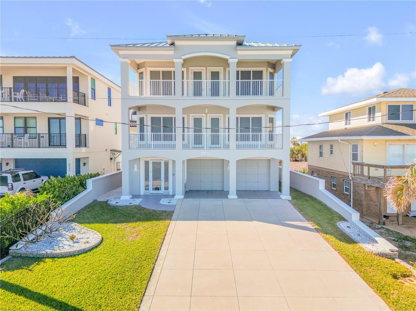 Situated directly on the oceanfront, this 3-story residence boasts an elevator and offers 4 bedrooms (convertible to 5 bedrooms) and 3.5 baths. Encompassing the desirable "no drive" area of New Smyrna Beach, this exquisite home has recently received a new roof in October 2021 and three new HVAC systems in May 2020. Meticulously crafted, the property has been thoughtfully designed to maintain its good-as-new appearance.

The ground level features a private beach walkover with benches for optimal viewing. Right inside the entrance on the ground level, you'll find a spacious foyer hall and a curved staircase leading up the south side. Adjacent to the staircase is a generously sized two-car garage. Additionally, the first floor offers a storage closet, two bedrooms, a bathroom, elevator access, and a west-facing outdoor patio.

Moving up to the second floor, you'll be welcomed by an open and airy layout. With its coffered ceilings, wood flooring, granite countertops, "Jack Busby" cherry cabinets, two double ovens, microwave oven and built-ins, this space exudes elegance. The second floor also features a separate dining area and a breakfast nook situated next to the island, complete with bar-height chairs. All of these spaces effortlessly flow together and provide breathtaking ocean views. A 30x10 covered porch extends the living area, further enhancing the coastal experience. Other amenities on this floor include an 8x6 laundry room with a sink, a half bath, and elevator access.

Ascending to the master floor on the third level, you'll reach the foyer area, which grants access to the private master suite through double doors offering stunning oceanfront vistas. The master suite itself has an attached oceanfront office or optimal fifth bedroom, and encompasses a lavishly appointed bathroom, featuring a soaking tub, walk-in shower, dual vanities, and an enclosed water closet. The suite is complemented by ample closet space with built-ins. Furthermore, the third floor accommodates an extra bedroom, another bathroom, and a sitting area or library that opens onto a west-facing balcony with views of sunsets and the Intracoastal Waterway.

This oceanfront residence showcases balconies and patios on both the east and west sides, allowing for optimum enjoyment of sunrise, rocket launches, beach activities, and sunset views complemented by refreshing evening breezes. An easy 2.5 block walk to the famous JB's fish camp. The home offers an array of special features, including 8' raised panel 1-3/4" thick solid doors, chair rails, double crown molding, stairstep scroll embellishments, two hot water heaters, one A/C unit per floor (three in total), sturdy plantation shutters, elegant wrought-iron spindles, and more. Do not miss out on the opportunity to view this well-maintained home, as it is truly a must-see.
