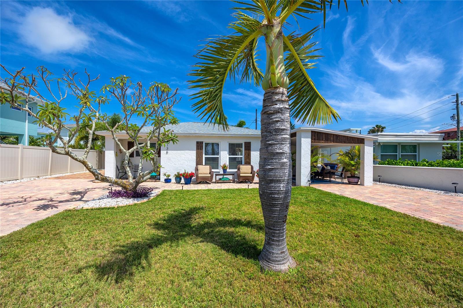 A block from the Madeira Beach shores, this fully updated coastal home delivers the kind of setup that works as a full-time residence, a second home, or rental with real earning potential. The 2024 roof carries a 15-year warranty. The whole home saw a fully permitted renovation in 2025 with all appliances replaced at that time along with a brand new AC, pool door alert system, and water heater, making it truly turnkey and low maintenance for years to come. Step inside and enjoy the open-plan living and dining area where wood-plank ceilings, fresh coastal paint, and luxury vinyl plank floors carry through the entire home. The kitchen is fully remodeled with white shaker cabinetry, quartz countertops, a tiled backsplash, and a stainless LG appliance suite including a slide-in range and built-in microwave. A peninsula with bar seating connects the kitchen to the living room, keeping the social flow easy whether you're hosting twelve or three. Bedrooms are well-sized with the same consistent coastal palette throughout. The bathroom has been fully redone, with stacked-stone accent walls, quartz vanities, matte black fixtures, and wicker pendant lighting tying in the coastal charm seen throughout the rest of the home. The outdoor living space is where this property shines. A covered front porch with an outdoor TV and wicker seating sets the tone before you even walk inside. The back of the house opens onto a paver patio with a saltwater pool, a corrugated metal tiki bar with wood-top counter and string lights, a dining area under a market umbrella, and separate lounge zones on both sides of the pool. A storage shed, artificial turf, and a stacked washer/dryer utility room with secondary refrigerator round out the back. Nearly everything stays: some backyard furniture, grill, washer, dryer, and second fridge are all included. Two paver driveways provide parking for multiple vehicles, and Madeira Beach residents receive city-wide parking passes valid at local beaches and John's Pass. The Gulf is one block away. John's Pass Village, with its restaurants, shops, water sports, and waterfront dining, is within walking distance. Golf cart-friendly streets make the whole neighborhood reachable without a car. Come check out this move in ready beach retreat today!