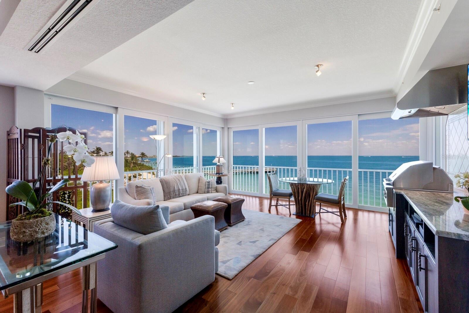 Perfectly positioned on the top floor of the highly coveted Harborshore enclave in Boca Bay, 801-3 Harborshore Drive is one of only two top floor residences within the community with no neighboring structure directly adjacent, offering a rare combination of privacy, abundant natural light, and unobstructed panoramic views of Charlotte Harbor and the surrounding landscape.  

This 3-bedroom, 3.5-bathroom residence with a separate office/den boasts over 3,000 square feet of air-conditioned living space, thanks to its fully enclosed and climate-controlled lanai—making it one of the largest condominium residences on Boca Grande. The result is an exceptionally spacious and flexible floor plan, ideal for entertaining, relaxing, and enjoying the island lifestyle to its fullest.

Brazilian cherry wood floors flow throughout the home, adding warmth and richness to the expansive open layout. The fully remodeled chef’s kitchen is a true centerpiece, featuring custom cabinetry, an elegant tile backsplash, a paneled Sub-Zero refrigerator, Wolf range, dual KitchenAid wall ovens, and an integrated TV blending style and function seamlessly. The custom pantry and laundry area offer additional cabinetry, counter space, and practical amenities, including a wine cooler, an additional sink, and a thoughtfully designed space for folding and hanging clothes.  

The enclosed lanai has been reinvented as a versatile entertainment space, complete with a wall-mounted flat-screen TV, gas grill, stone countertops, custom cabinetry, and a commercial-grade exhaust hood—all while maintaining seamless sightlines to the breathtaking harbor views.

The primary suite is a private bayside retreat, offering dual walk-in closets with custom built in closet systems, a serene screened porch overlooking the water, and a beautifully remodeled en-suite bathroom featuring shell stone floors, a spacious walk-in shower, a custom dual-sink vanity, and premium fixtures. Each guest bedroom includes its own updated en-suite bath, while the front guest room enjoys a private terrace with views over Boca Bay’s manicured landscape.  

Peace of mind and year-round comfort are ensured with impact-rated sliding glass doors, electric roll-down storm shutters, plantation shutters, and motorized window treatments throughout the home. Additionally, the building received a new roof in 2023, adding another layer of protection, and long-term security. Additional features include elevator access, a private garage and storage closet, upgraded LED lighting, and refined finishes and fixtures that complement the home's elegant coastal aesthetic.
Just a short stroll or golf cart ride brings you to the exclusive Boca Bay Pass Club, with access to waterfront dining, fitness facilities, tennis courts, and the beach. Residents also enjoy an array of amenities including multiple swimming pools, pickleball courts, short-term boat dockage, a private fishing pier, and a Gulf-front Beach Club.