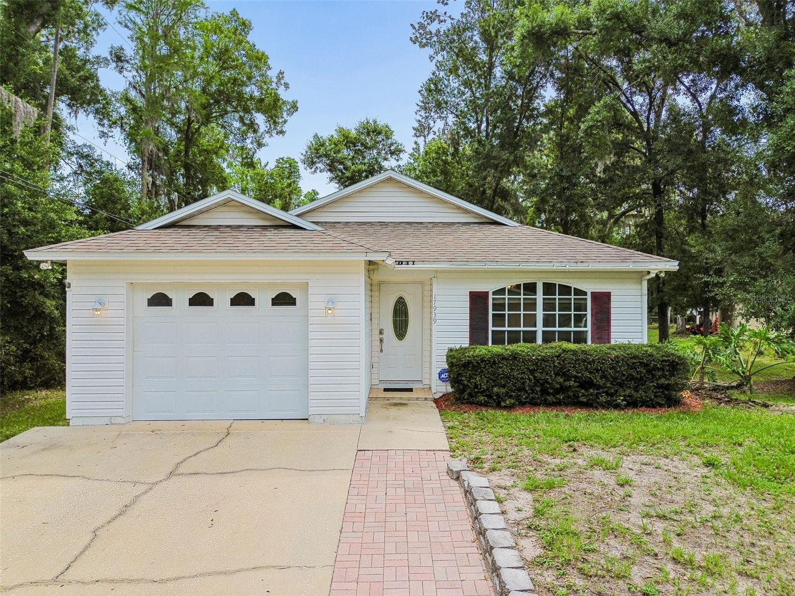 Tucked beneath mature trees with a peaceful, private feel, this charming single-story home offers bright interior spaces, easy everyday flow, and inviting outdoor living in the heart of Lutz. From the welcoming front entry to the covered rear patio, the home is designed for comfortable living while embracing the natural beauty of its surroundings. Inside, the spacious living area is filled with natural light and features large windows, neutral finishes, recessed lighting, and an architectural tray ceiling that enhances the sense of space. The kitchen offers abundant white cabinetry, generous counter space, breakfast bar seating, white appliances, and a functional layout that remains connected to the main living and dining areas—ideal for both everyday living and entertaining. The bedrooms provide comfortable accommodations with ceiling fans, ample closet storage, and peaceful views of the surrounding landscape, while the bathrooms feature clean, neutral finishes and practical layouts. The one-car garage provides additional storage and utility space. Step outside to enjoy the covered back patio overlooking a spacious backyard shaded by mature oaks and lush Florida greenery, creating a relaxing setting for morning coffee, outdoor dining, or simply enjoying the peaceful surroundings. An exceptional opportunity exists for buyers seeking additional space, privacy, or future flexibility, as the adjacent rear parcel is also available for purchase separately (MLS #TB8514870). Acquiring both properties would create a significantly larger combined footprint, and giving you nearly 1/2 acre.  This offering expanded possibilities for outdoor living, gardening, recreational use, storage, future improvements, or long-term investment potential, subject to applicable zoning and county regulations. Conveniently located near SR 54, US-41, and the Suncoast Parkway/Veterans Expressway, this property offers easy access to Tampa International Airport, downtown Tampa, major employment centers, shopping, dining, healthcare facilities, and everyday conveniences. Nearby destinations include Tampa Premium Outlets, The Shops at Wiregrass, KRATE at The Grove, numerous golf courses, parks, and recreational amenities throughout Pasco and Hillsborough Counties. Combining privacy, natural beauty, expansion potential, and a highly accessible location, this property presents a unique opportunity to enjoy the best of relaxed Florida living while securing additional land in one of the area's most desirable growing markets.