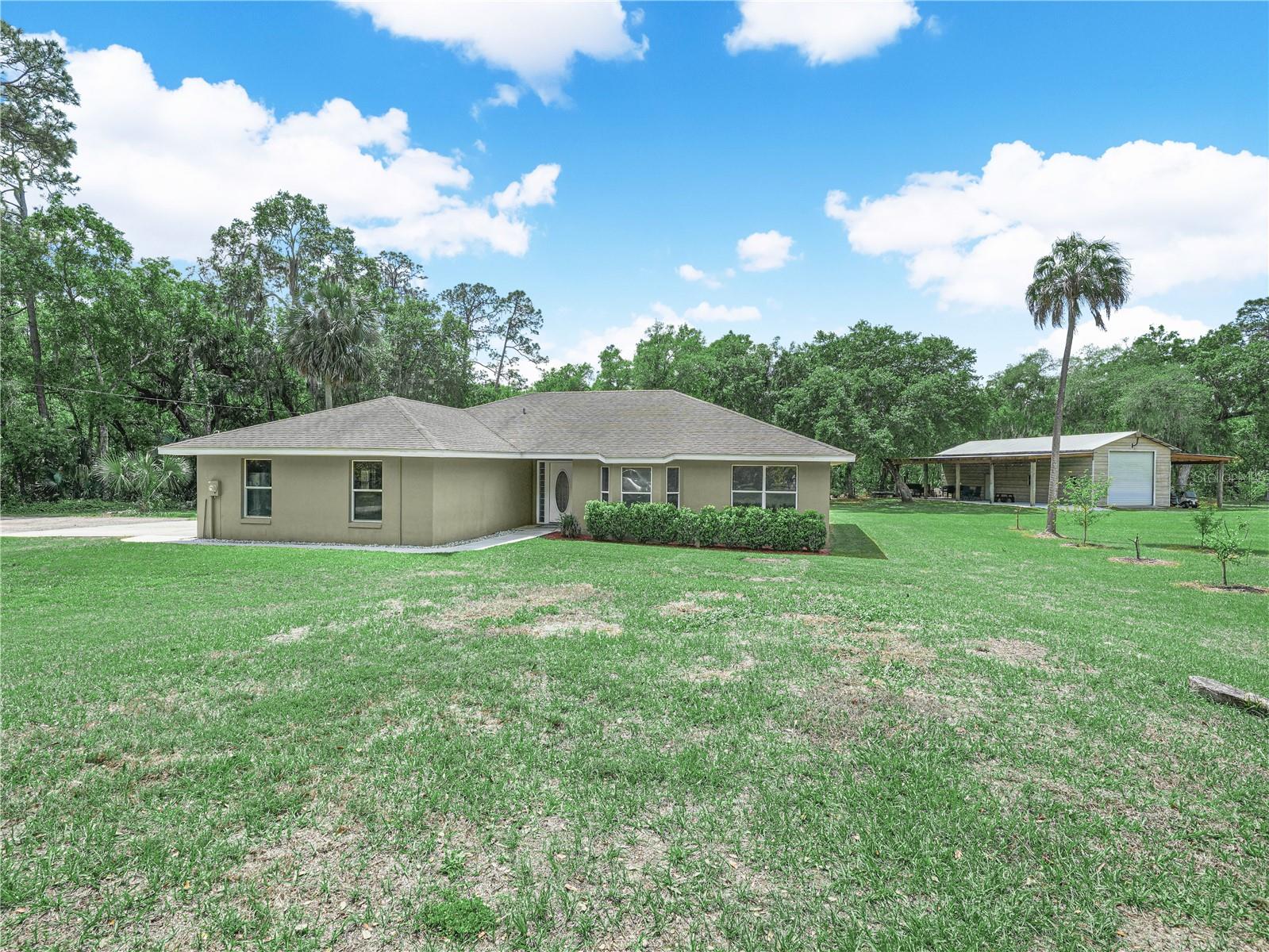 Situated on 2.3 acres, fully fenced and gated. This 3-bedroom, 2.5-bath home offers 1,700 square feet of comfortable living space along with a large workshop/garage. Walking in the front door, you'll step into the living room with vaulted ceilings and stone fireplace that flows into the kitchen and breakfast nook. The dining room is conveniently located just off the kitchen and entryway. The split floor plan features two bedrooms and a full bath on one side of the home, with the master suite privately located on the opposite side of the home. The master bedroom includes a large walk-in closet, sliding glass doors leading to the back patio, and a freshly remodeled bathroom with a large walk-in shower. Outside, the 20x50 workshop features a 12'x12' garage door and 15x50 covered areas on both sides, with one side having a concrete slab and lighting. The property is on well water and septic and also includes a brand-new water heater. Located just minutes from Camp Mack, with a public paid boat ramp giving you access to the renowned Kissimmee Chain of Lakes. This property delivers the ideal balance of rural privacy and outdoor recreation. Load up your boat and take full advantage of nearby waterways, while still enjoying the peace of being away from the hustle and bustle of the city and staying conveniently close to everyday necessities.