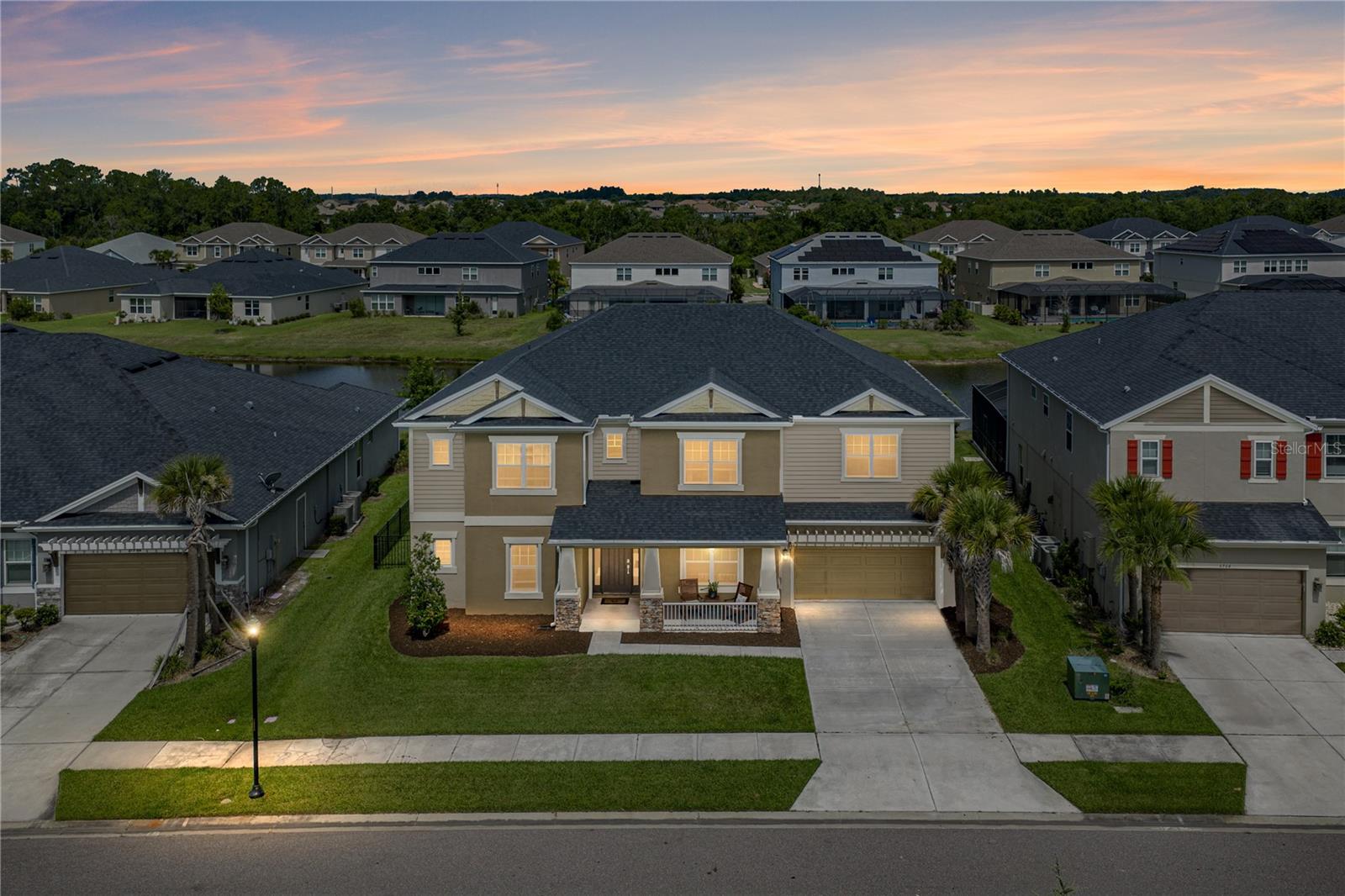 Some homes are built around the way people actually want to live, and this pond-view pool home in Bradbury at Watergrass is exactly that. Start the day with sunrise from the east-facing front porch, end it poolside with sunset views over the pond, and enjoy a 6 bedroom, 3.5 bath layout with the space, privacy, and gathering areas a large household needs. Located in a gated section of amenity-filled Watergrass, this two-story home brings together luxury finishes, multiple bonus living spaces, a heated pool and spa, and a 3 car tandem-style garage. A stone-accented exterior, outdoor lighting, lush lawn, and cozy covered front porch create a warm arrival before the home opens into a bright interior with soaring ceilings. Triple sliding doors fill the expansive living room with natural light and frame views of the pool deck, while built-in shelving surrounds the electric fireplace for a polished focal point at the center of the home. Just beyond the living room, the gourmet kitchen lives up to the name with 2 center islands, a double built-in oven, cooktop with stainless steel range hood, pendant lighting, butler’s pantry, walk-in pantry, breakfast bar seating, and an eat-in dinette for casual meals. The formal dining room sits nearby for more intimate gatherings, while a dedicated home office across the hallway gives the first floor a quiet place for work or homeschooling. The primary suite is also located on the first floor and enjoys pool views, 2 walk-in closets, and a spacious ensuite bathroom with 2 separate sinks, a vanity seat, soaking tub, and walk-in shower. A guest half bathroom completes the main level before the carpeted staircase leads upstairs. On the second floor, the home expands into two generous bonus areas. An open loft gives flexibility as an extra living room, playroom, game room, etc., while the separate media room features carpet flooring, built-in shelving, and an electric fireplace for cozy movie nights in. Five additional bedrooms are split into two sections upstairs, giving the layout excellent versatility. Bedrooms 2 and 3 each include walk-in closets and share a walk-through Jack and Jill bathroom. Bedrooms 4, 5, and 6 offer great closet space, with 2 featuring walk-in closets, and they sit near the home’s third full bathroom with a tub/shower combination. Outdoor living in this home is another opportunity to bring everyone together. The expansive paver pool deck surrounds the sparkling heated pool and spa, with the fenced backyard and pond view creating a beautiful backdrop for evening meals, weekend gatherings, and everyday adventures at home. There is room for pets, play, lounging, grilling, and soaking in the sunset with a water view. The gated Bradbury at Watergrass places you just minutes from community amenities, including pools, basketball courts, dog park, playground, fitness center, and more. This home offers the space, layout, and amenities large families are hoping to find- all in a central location. Call today to schedule your private showing!