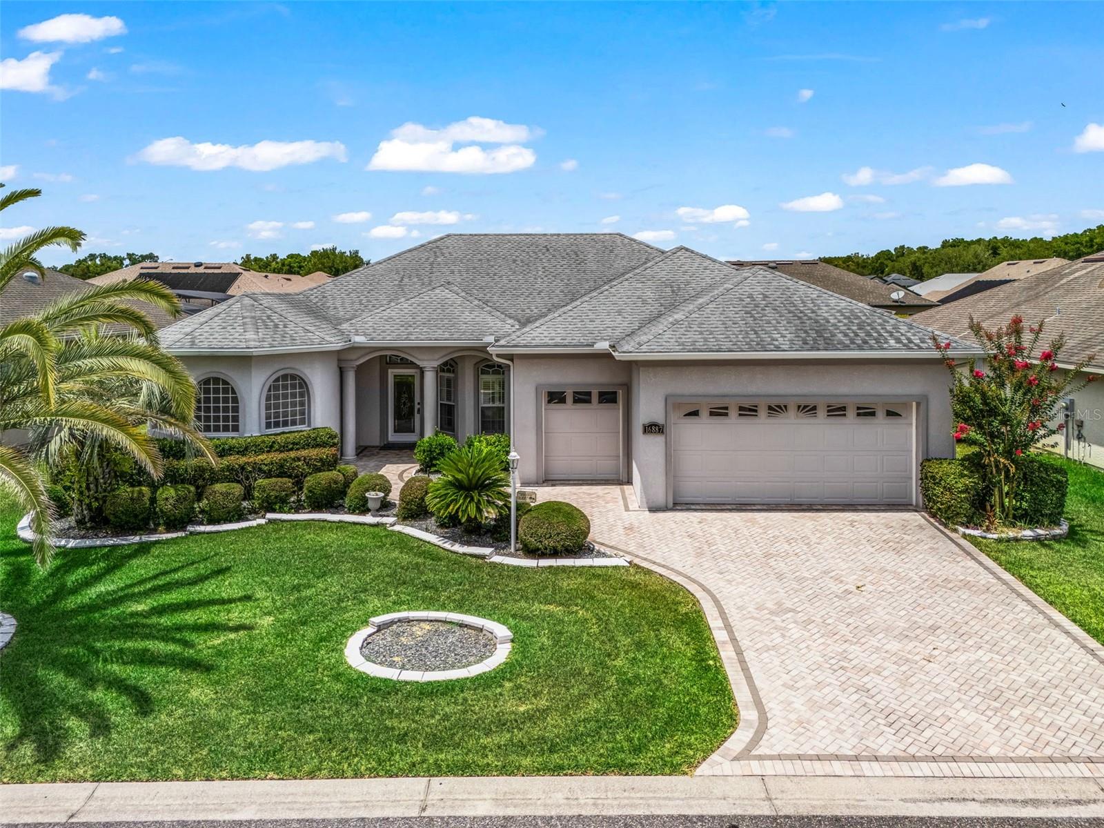 Virtually Staged. Stonecrest is a 55+ gated golf course community with all the amenities and 4 pools (one indoor), and just a Bridge Away By Golf Cart To The Villages!  Exceptional 3/2 Concrete, Block, and Stucco Spruce with a 2 Car + Golf Cart Garage!  You will Love the New ROOF 2026! Open Concept and Split Floor plan, Rear Privacy, and Tremendous Curb Appeal featuring Meticulously Maintained Professional Landscaping, Designer Paver Driveway and Walkway, and Covered Front Entrance with an Elegant Leaded Glass Door! The Open Concept and Split Floor Plan, with plenty of Space, and Natural Light, making the Spruce model just perfect for Entertaining Friends and Family! This well appointed home boasts Upgraded Designer Light Fixtures, Soaring 10 ft ceilings, Glowing Laminate Flooring, and an 34 x 12 Glass Enclosed Lanai with a 34 x 10 Birdcage Enclosed Back Patio that backs up to a Privacy Wall!  The Dining area flows to the Spacious Living area, creating a warm, and inviting gathering space.  The Large Eat in Kitchen showcases Gorgeous Quartz countertops, Stainless appliances, Rich Wood cabinetry, Center Island, 4 x 4 Pantry closet, access to the Lanai, and combines with the Huge 20 x 13 Family room with Tile flooring, sliding door access to the Lanai!  The Split Floor Plan affords maximum Privacy for both the owners and their guests, as the Primary Suite is located at the opposite side of the home from the guest bedrooms and guest bathroom. The Luxurious Primary Suite boasts Private French Door Entry to the Lanai, 2 Walk in Closets, and an En Suite Bathroom, featuring a Two Sink Vanity, Soaking Tub, Walk in Shower, and Private Water Closet.  The Guest bedrooms feature nice size built in closets, and provide your guests with a comfortable living space.  The Massive Glass Enclosed Lanai offers plenty of room for Multiple Seating Areas, and provides an Exceptional Additional Living area!  A Fantastic added addition to the Outdoor Living Experience in the 34 x 10 Birdcage Enclosed Back Patio with the backyard featuring a rare privacy wall!  The large 2 Car + Golf Cart Garage has plenty of room for storage, and has additional shelving!  New Irrigation System December 2025 ($1,111.80), Contract with Massey Pest Control.  Stonecrest is a 55+ gated golf course community with all the amenities, pools, pickleball courts, softball, 18 hole championship golf course, Broad Stripes Golf & Social Club and over 80 different clubs to join! As a private gated golf course community, you can expect a high level of privacy and security. Overall, this home offers a combination of Fantastic Outdoor Space, Luxurious Features, a Terrific Location, and a Secure Community Setting. A WONDERFUL LIFESTYLE AWAITS YOU IN STONECREST!