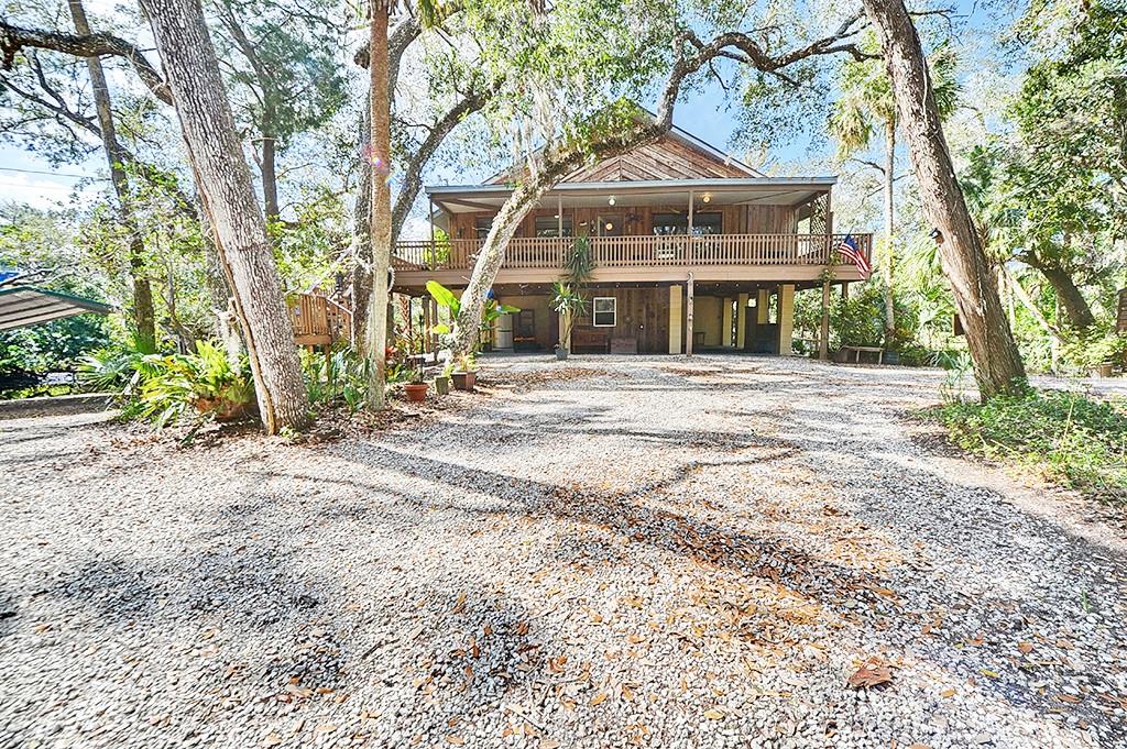 Location! Location! Location! And another price reduction! Come see for yourself! Motivated seller! This home creates an opportunity for someone who sees value & vision to take on projects while investing in this Waterfront home on 1.26 acres. More land available for purchase. This unique retreat is nestled in nature, offering 180 feet of water that wraps around the home. Grassy fenced in yard around the water is perfect for your pets! Two-bedroom Two-bathroom main home upstairs with separate 1 bedroom 1 bathroom, living area & kitchenette downstairs. Perfect mother-in- law or rental apartment opportunity! A comfortable residence surrounded by lush trees, wildlife, and peacefulness. It's a sanctuary where you can unwind, recharge, and embrace nature's beauty all day, every day. Turn into your long circular driveway that gracefully meanders through the lush landscape, leading to your private oasis. The home is perfectly positioned offering stunning views from nearly every room. Elevated high above the ground, you can look down over your estate and enjoy the peaceful surroundings. Step outside, and you’ll be enchanted by your very own private lagoon—a peaceful sanctuary where manatees come to give birth each year and playful porpoises frolic in the water. Deer will be seen, owls will be heard, mullet will jump and hummingbirds will flutter around you. Navigate from your boat dock to the Gulf of Mexico or to the clear spring waters of the Homosassa River. Go by golf cart or boat to many tiki bars & restaurants and enjoy everything Old Homosassa has to offer. This haven offers the best of both worlds: total tranquility amidst mature oaks, palm trees & nature along with quick access to local delights. One can change a home, but you can't change the surroundings. The very best of ALL worlds are waiting for you here. Additional 1.21 vacant land parcel available to purchase with the home on the other side of the lagoon.