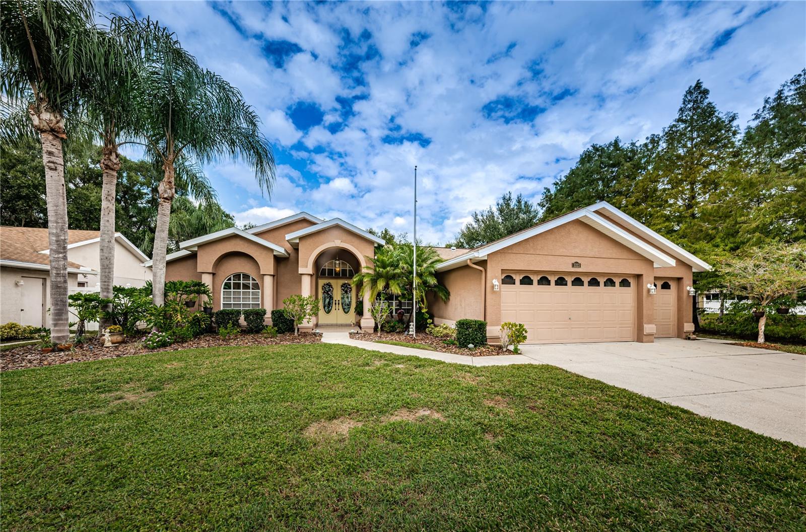 This impressive property in Ellington Estates, cherished by its original owners for 25 years, offers a custom-built home with three bedrooms, two and a half baths, and versatile spaces like a den, dining room, and breakfast nook. The spacious backyard is a tropical oasis featuring a pool and patio area, and the living room includes a cozy fireplace and pocket sliding doors that open to the patio. With a three-car garage, an indoor laundry room, and a workshop in the garage, it's both functional and convenient. Recent updates include a new roof in 2019, a water heater in 2009, and AC in 2013. The master bedroom is a retreat with French doors leading to the pool deck, and the den can be transformed into a fourth bedroom. The master bathroom is luxurious, offering a standalone shower and a Jacuzzi tub. This home is centrally located near restaurants, shopping, parks, and the popular Starkey Ranch community. As you enter, you'll be captivated by the view of the pool, and the quaint community off State Road 54 provides a warm and welcoming atmosphere. It's a home ready for new owners to create their own memories and love it as much as the previous owners did. With a large three-car garage, it's perfectly equipped for those with multiple vehicles or a need for extra storage space. This property combines a serene setting with the allure of community living, making it an ideal place to call home.