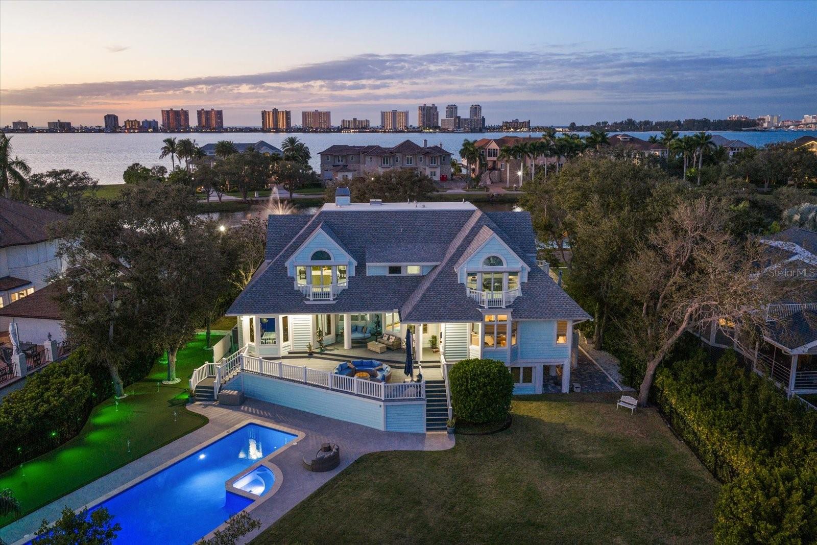 Florida luxury living reaches its pinnacle behind the private, guarded gates of coveted Belleview Island in beautiful Belleair, where this extensively remodeled and thoughtfully renovated residence makes a striking first impression with exceptional curb appeal and a paver driveway welcoming you home. Perfectly positioned to capture both breathtaking sunrises and glowing sunsets, the home is wrapped in balconies that frame sweeping water, golf course, and tropical views at every turn. Inside, an open and inviting interior unfolds in soothing neutral tones, enhanced by custom ceilings, detailed moldings, and an abundance of natural light. The desirable floor plan offers a formal living room anchored by an electric fireplace for cozy evenings, while the dining room is adorned with custom built-ins and showcases panoramic Intracoastal views stretching across to the bluffs of Belleair. A lower-level guest bedroom enjoys serene pond views and a private ensuite with a quartz vanity, offering comfort and privacy for visitors. The spacious family room features built-ins, a gas fireplace, and stunning water views, flowing seamlessly into a truly dream-worthy kitchen complete with a quartz island with seating, top-of-the-line stainless steel appliances including a natural gas cooktop, Viking refrigerator, and two dishwashers, plus a private desk overlooking lush tropical foliage. A generous laundry room with sink, abundant storage, dumbwaiter, and access to a screened “catio” adds both convenience and charm. Upstairs, the primary suite is a peaceful retreat with spectacular Belleair Country Club golf course views and sunrises over the Intracoastal enjoyed right from bed, complemented by a huge custom closet, electric blinds, and a spa-like ensuite featuring custom tile, a double sink vanity, walk-in shower, and a luxurious soaking tub. Additional bedrooms are equally well appointed, each offering its own unique luxury, from tranquil pond views to pool and Intracoastal vistas, ensuring family and guests enjoy both privacy and refined comfort. A versatile bonus room with pond views and a private balcony provides the perfect space for a home office or creative studio. The downstairs uninsurable area is designed for enjoyment and flexibility with a theatre and entertainment space, room for three cars and a golf cart, and ample space for a home gym, while a brand-new three-car garage with split A/C brings total covered parking to six vehicles. Outdoors, a resort-style setting awaits with a newly resurfaced pool surround, a 2022 seawall, and a dock inviting endless days soaking up the Florida sunshine on the water. Completing this exceptional offering are a whole-house generator, new outdoor lighting and irrigation, a comprehensive security system with cameras, impact windows and an electric car charger, all just moments from Belleair Country Club, The Pelican Golf Club, local restaurants, boutique shopping, two airports, and the sparkling beaches that make this area so sought after.