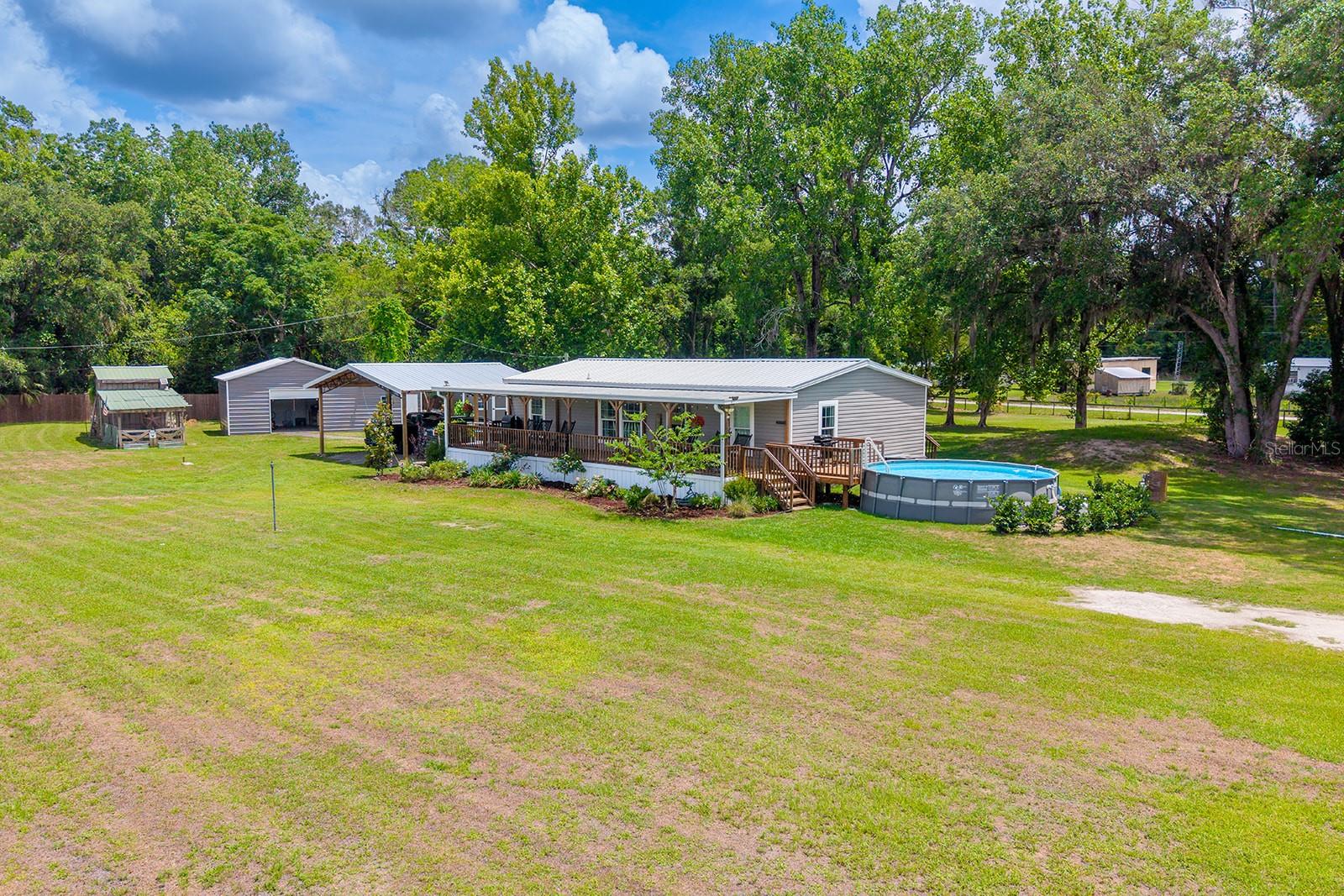Tucked away on 1.91 fully fenced and gated acres in Cross City, this well-maintained 3 bedroom, 2 bath home offers the perfect blend of comfort, functionality, and country living. Step inside to find a clean and inviting interior featuring upgraded kitchen appliances and a layout designed for everyday living and entertaining alike. Outside, the property truly shines with covered porches and a spacious deck overlooking the above-ground pool — the perfect spot to relax and enjoy peaceful North Florida evenings. For those needing extra workspace or storage, the large metal workshop provides endless possibilities, while the insulated shed with AC makes an ideal hobby room, office, or additional storage space. Animal lovers and homesteaders will appreciate the fully functioning chicken coop already in place. Additional features include RV hookup access and irrigation for the landscaping, helping keep the property looking its best year-round. With plenty of room to spread out, this property is ideal for those seeking privacy, outdoor living, and space for all their toys and hobbies. Located in the heart of Dixie County, Cross City offers a laid-back small-town atmosphere with convenient access to the Gulf Coast, nearby springs, fishing, boating, hunting, and outdoor recreation. You’re also just a short drive from Chiefland for shopping, dining, and everyday conveniences while still enjoying the peace and quiet of country living