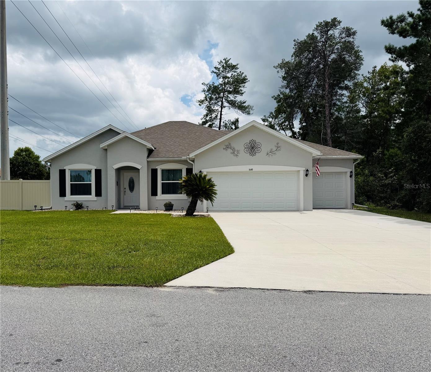 Welcome to this exceptional single-family home, built in 2022 and situated on a generous 0.54-acre lot in the desirable Kingsland Country Estates community. Designed with both comfort and entertaining in mind, this move-in-ready home features a bright, open-concept floor plan with stylish finishes throughout.  The heart of the home is the beautifully appointed kitchen, showcasing striking dark blue cabinetry, elegant quartz countertops, and ample space for gathering with family and friends. The open living room flows seamlessly to the expansive backyard, making indoor and outdoor entertaining effortless. The home also features three bedrooms, two bathrooms, and a versatile den/office that is perfect for working from home, a playroom, or a flex space.  The spacious indoor laundry room includes cabinetry, adding both convenience and functionality.  One of the property's standout features is the oversized three-car garage, offering exceptional flexibility for vehicles, storage, or a workshop. The garage includes custom built-in cabinetry with granite countertops, creating an ideal workspace. Measuring approximately 20' x 24.9' and 10' x 29.7', it easily accommodates a full-size pickup truck while still providing abundant room for tools, equipment, or recreational gear.   Step outside to enjoy the oversized rear patio, which is partially covered for year-round comfort and includes an extended paver area that's perfect for grills, an outdoor kitchen, or additional seating. The fenced backyard provides a secure space for pets to play, while the natural area beyond the fence offers added privacy and a peaceful backdrop.  Vinyl Fence provides privacy. from the road.   With modern construction, thoughtful upgrades, abundant outdoor living space, and a layout designed for entertaining, this beautiful home offers the perfect combination of style, functionality, and privacy.