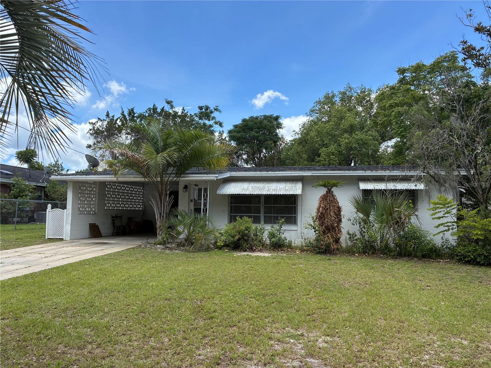 This Concrete Block Fixer Upper sits on a generous 1/4 acre lot. Large eat-in kitchen, covered patio, carport with storage, detached block storage building, and a primary bedroom with space to add a bathroom.