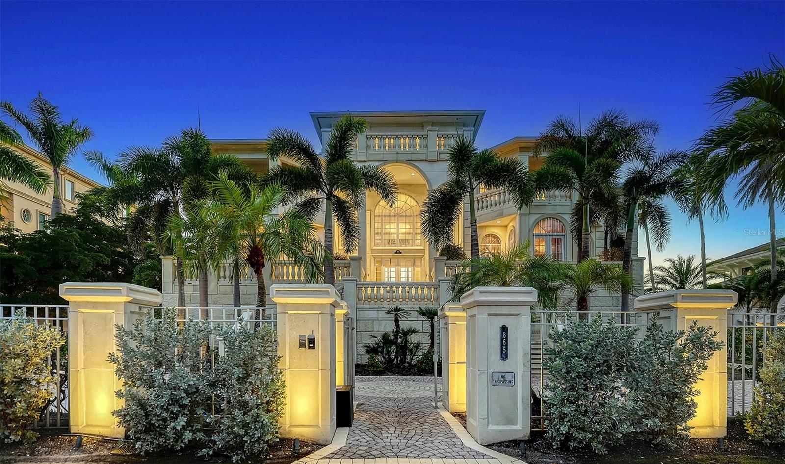 Regent’s Court: The Pinnacle of Luxury on Florida’s West Coast
Regents Court: Where Legend Meets Luxury

Beyond the gates of the Longboat Key Club lies an estate that doesn’t just live — it performs. A dramatic masterpiece perched on Florida’s west coast, this estate commands over an acre of pure beachfront with 150 feet of unspoiled Gulf frontage, where sky and water fuse in ever-changing hues at dawn and dusk.
Your arrival is nothing short of cinematic: majestic wrought-iron gates part to reveal a sweeping driveway paved in artistic stone, each curve leading closer to the heart of the home. A side-entry garage, cavernous in its capacity, hides generous storage; beside it, a full-house generator promises unbroken comfort even when the world goes dark.
Inside, every surface and silhouette feels sculpted for impact. Cream marble floors echo with light. Designer lighting drapes each room in mood and elegance. Premium stainless steel appliances anchor a gourmet kitchen, with a bar area that’s built for both intimate soirées and lavish celebrations. Across stately arches, French doors open into an office and dining space. 
Ascend via elevator through all four levels, each floor unveiling rooms with cathedral ceilings, balconies with sweeping views over the Gulf. The two-story library has custom woodwork. Adjacent to the large primary bedroom is the super-master bath with both tub and shower framing the Gulf in panoramic glory.
On the second living level are three guest suites with private porches that render a daily spectacle — mornings bathed in soft dawn light over the sand dunes and the Gulf, evenings lit by fading sun dancing across the waves. French doors open wide, blurring the boundary between indoors and the beach. 
The third living level includes an all inclusive guest quarters—your private sky-retreat. Two bedrooms, two baths, a full kitchen, a spacious living and TV room.  From its large, sweeping porch, the views stretch across Sarasota Bay and the Gulf’s glassy expanse. By day the Bay shimmers under sunlight, by dusk the city lights begin their soft glow. This is a space where family, friends—or guests—can escape, entertain, or simply soak in nature’s most breathtaking performances.
Outside is not secondary, but rather the heart of this sanctuary. Lush tropical landscaping surrounds the estate.  There is a NCAA lap pool with motorized cover, a deck edged with gas torches, fire pits that flicker under the stars. There’s an outdoor ice tub plus an outdoor kitchen with refrigerator and a gas grill. A special gym on the second floor is cooled to perfection, central control at your fingertips. Roll-safe shutters provide safety without sacrificing style.
At every moment, this home evokes a rare elegance — you’re not just observing the sunset over the Gulf, you are enveloped by it. Minutes from Sarasota, St. Armand’s Circle, Anna Maria — yet here, time moves differently, more luxuriously.
This is not just a home. This is a legacy.