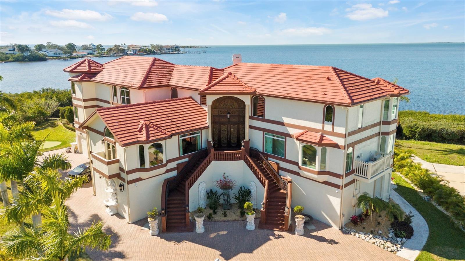 MEDITERRANEAN WATERFRONT MASTERPIECE MEETS COASTAL LUXURY. Discover unparalleled elegance in the exclusive, gated community of Harbour Watch. This impressive Tarpon Springs estate is a masterwork of craftsmanship, where meticulous architectural detail meets a serene waterfront lifestyle. Experience Florida living at its finest! Upon arrival, you’ll be impressed with all the architectural details. The handcrafted front door immediately sets the tone for the craftsmanship inside. The home’s interior is a curated collection of art, adorned walls with ornamental molding and trim, a dramatic staircase with custom iron railing, and high ceilings. The ambiance is elevated by the exquisite crystal chandelier and fireplace. Marble and hardwood flooring flow throughout the home. Every detail of this home is crafted to deliver elegance, functionality, and comfort. This stunning home features 6 bedrooms, 5 1/2 bathrooms, and a 6-car garage. With 6,595 sq ft of living area and over 12,000 sq ft of total area. Enjoy breathless Sunsets and Moonsets surrounded by 257 feet of unobstructed waterfrontage overlooking the Gulf of America. The layout is both versatile and inviting. At the heart of the home, the gourmet kitchen showcases wood cabinetry, built-in pantry cabinets, and premium Sub-Zero appliances. The kitchen flows into the spacious family room and wet bar, creating the perfect indoor-outdoor living experience with an outdoor fireplace. Adjacent to the formal dining room, you will find a magnificent private office featuring intricate crown molding and wood paneling. Walk up to the third level or take the elevator, and you will encounter three spacious bedrooms, including the luxurious primary suite, a serene retreat with oversized walk-in closets, a separate make-up vanity room, and a spa-style bathroom adorned with exquisite finishes. Panoramic views all around your private balcony with a seating area to enjoy your evenings. Smart home features abound, including over $800,000 in integrated Josh-AI technologies that control the state-of-the-art home theater, audio/video systems, motorized shades, music, lighting, and pool features, all seamlessly controlled at your fingertips or with voice commands. Step outside and experience a truly entertainer’s paradise. A lavish saltwater pool with an integrated spa, sundeck, water fountains, sculptures and cabana creates a resort-like atmosphere, complete with plenty of outdoor seating areas perfect for year-round entertaining. The outdoor oasis takes resort living to the next level. Enjoy the full outdoor kitchen and the abundant deck area for hosting the ultimate pool party. Enjoy swimming or lounging, while your private kayak launch gives you easy access to the water. For the fishing enthusiast, the private dock is a front-row seat to nature, where you can watch dolphins, birds, and fish up close. Additional features include two laundry rooms, a finished garage with a game room, a putting green, and a private English garden. Community amenities include a renovated clubhouse, swimming pool, tennis and pickleball courts, playground, and butterfly garden. Conveniently located just minutes from Howard Park, Sunset Beach, 45 minutes from Clearwater Beach, St. Petersburg, and Tampa Airport. Schedule your private showing today and experience the lifestyle you’ve always dreamed of!