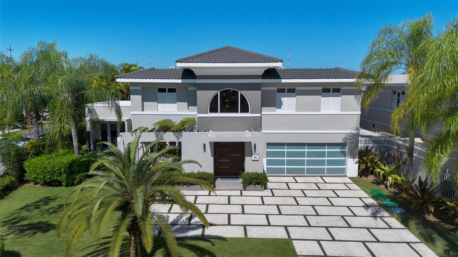 Discover this delightful estate in the highly sought-after Palma Real neighborhood of Guaynabo. Situated on a private corner lot, this home offers both privacy and elegance, with 5,409s/f of gross living area. 
This charming home features a welcoming driveway, offering ample space for parking, and is framed by beautifully landscaped gardens that add to its curb appeal. The traditional shingles on the roof complement the home's timeless character while providing durability and a classic aesthetic. 
The high ceilings and marble floors throughout create a sense of spaciousness and luxury. The  German Poggenpohl kitchen is a masterpiece, blending style and functionality seamlessly. The master suite is a true retreat, with a spectacular walk-in closet that adds a touch of opulence. The redesigned patio and pool area feature sleek, modern lines, offering a perfect space for outdoor living and entertainment.
Residents of this exclusive community enjoy unparalleled amenities, including a state-of-the-art gym with professional trainers, group exercise classes, beach tennis, a sparkling pool, basketball court, and two tennis courts. The dedicated playground and 24/7 security further enhance the lifestyle offered here. This is more than a home—it’s a lifestyle.
Live in comfort and style, with everything you need right at your doorstep.