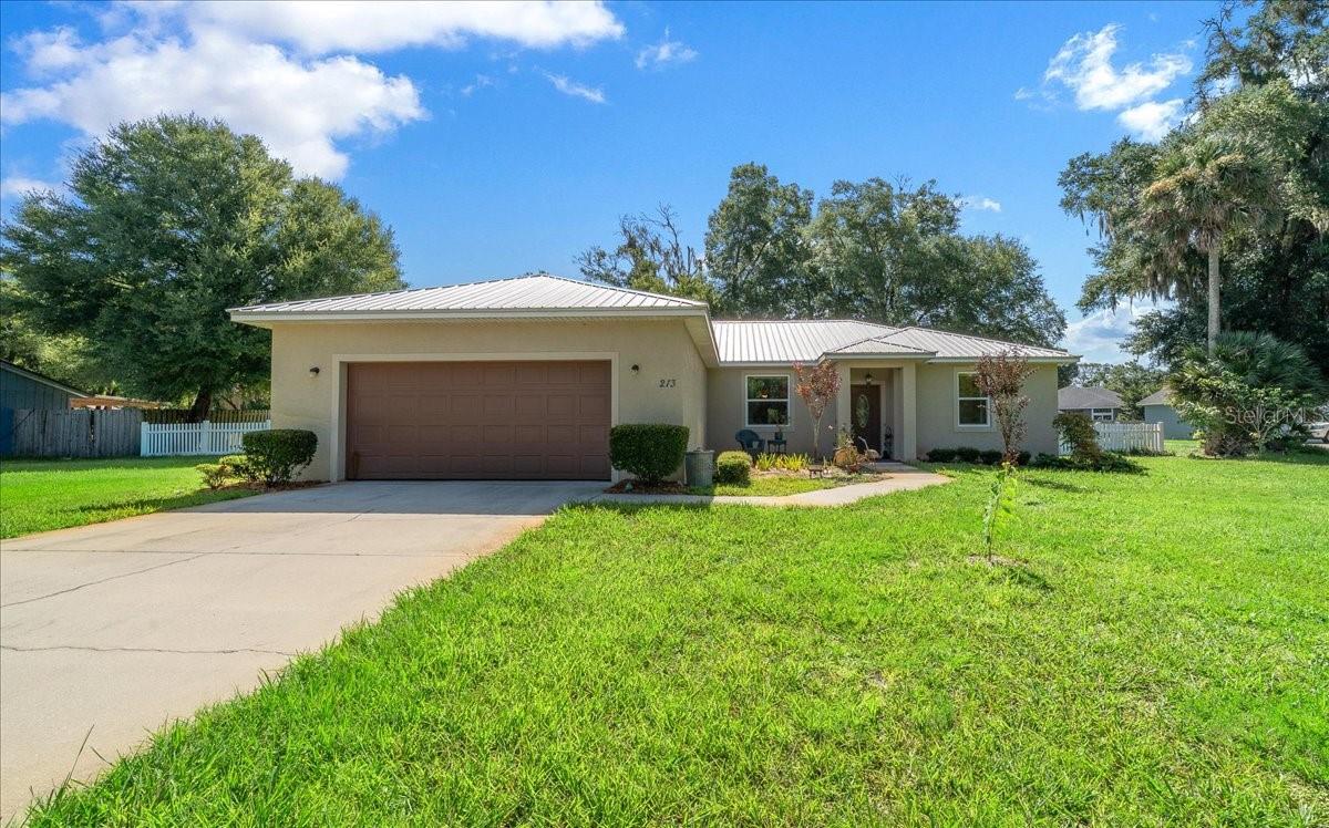 Welcome to this beautiful 2018-built home offering 1,795 living square feet of thoughtfully designed space with 3 bedrooms, 2 bathrooms, and a 2-car garage on .52 acre. Featuring a durable metal roof and an open-concept floor plan, this home is perfect for both everyday living and entertaining. The spacious living room showcases vaulted ceilings, creating a bright and airy atmosphere that flows seamlessly into the stunning kitchen. The chef-inspired kitchen features a large center island, granite countertops, abundant cabinetry, and plenty of workspace for meal preparation and gatherings. The generous primary suite offers a peaceful retreat with a walk-in closet and a private en suite bathroom complete with dual granite vanities, a water closet, and ample storage. The two additional bedrooms provide flexibility for family, guests, or a home office. Both bathrooms feature granite countertops, and the convenient inside laundry room adds to the home's functionality. Step outside to the large covered rear patio overlooking a huge, fully fenced backyard—ideal for pets, play, gardening, or entertaining. Two storage sheds provide plenty of room for tools, equipment, and outdoor gear. Located in the heart of DeLand, close to SR 44, this home offers the perfect blend of comfort and convenience. Known for its charming brick-lined streets, beautifully preserved historic architecture, vibrant downtown, local restaurants, art galleries, and unique boutiques, DeLand offers a welcoming small-town atmosphere with a lively arts and cultural scene. Outdoor enthusiasts will enjoy nearby parks, nature trails, and recreational opportunities, while Florida's beautiful east coast beaches are just a short drive away. Don't miss your opportunity to own this move-in-ready home in one of Central Florida's most desirable communities!