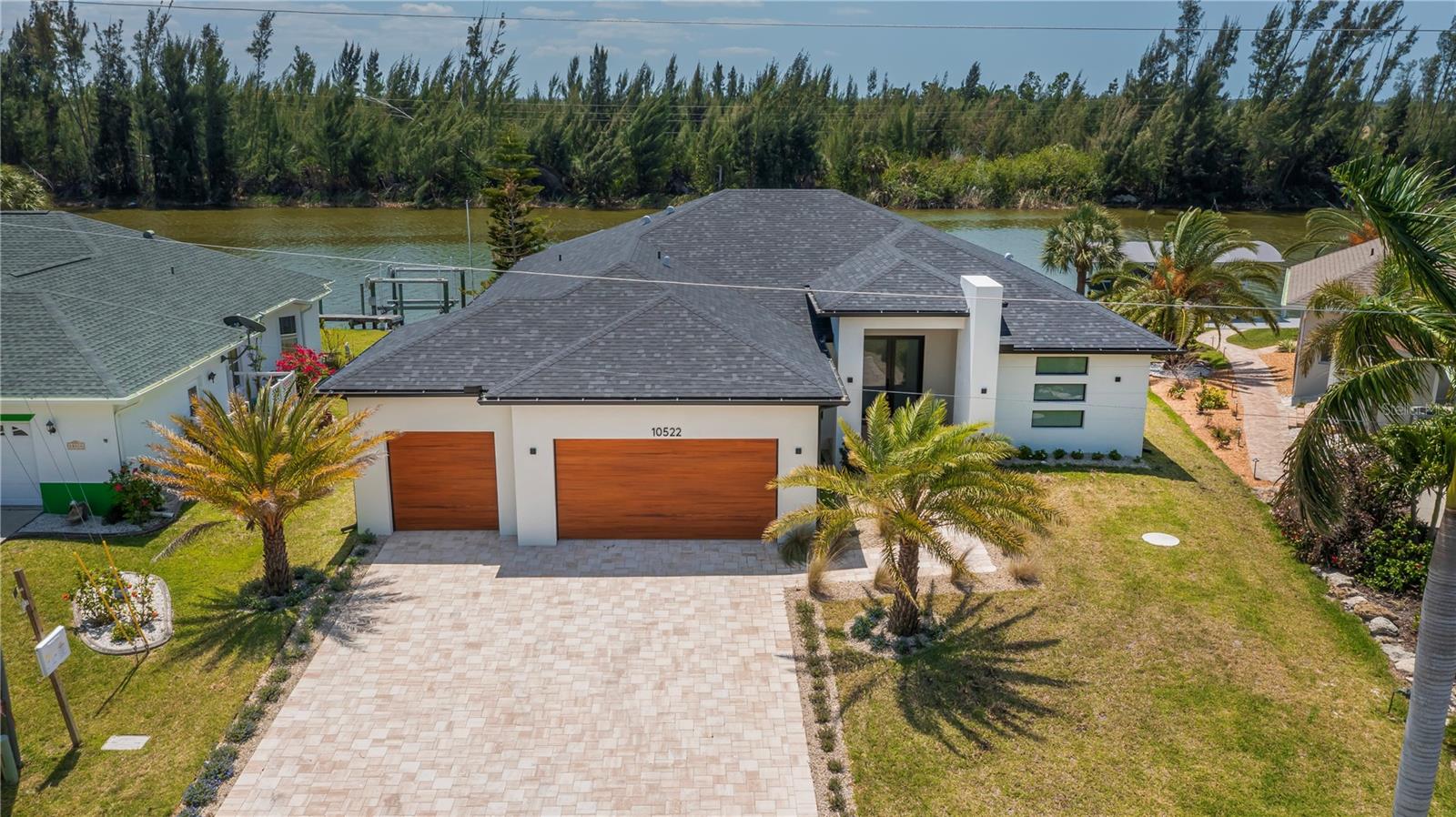 EXPERIENCE UNPARALLELED SAILBOAT ACCESS in this stunning custom built 4 bedroom, 3 bath, 3 car garage pool home in the prestigious  waterfront community of South Gulf Cove. Overlooking a STUNNING wide water canal, this home offers exquisite privacy, breathtaking southern exposure sunsets, and serene natural habitat views, an idyllic Florida lifestyle come true. This sleek, modern masterpiece showcases clean lines and incredible curb appeal with a contemporary paver walkway and driveway, manicured landscaping, soaring entryway, custom doors, and distinctive vertically stacked horizontal windows, pure elevated modern elegance. Step inside the foyer to an open floor plan flooded with natural light, tray ceilings, designer lighting, plank style porcelain tile flooring, and low profile linear air vents, all crafted with superior finishes throughout. The spacious living room features a dedicated theatre wall with a sleek modern fireplace and sliding doors that seamlessly connect indoor and outdoor living to the sparkling pool and stunning water views. Your chef worthy kitchen, adjacent to a formal dining room, boasts quartz counters and backsplash, stainless steel appliances, a chimney range hood, dome pendant lighting, soft-close cabinetry, decorator hardware and a spectacular waterfall edge breakfast bar, perfect for fine dining or effortless entertaining. The versatile den, enclosed with sleek frameless glass double doors, fills with ambient natural light and offers panoramic water vistas, making it ideal for an office or hobby room. The zen inspired primary suite is a private retreat with patio, pool, and outdoor kitchen access, tray ceiling, sky enhancing clerestory window, California Closets, and a spa like ensuite bath. The luxurious bath features a sculptural freestanding tub, high end double vanity, arched mirrors, low threshold Roman shower with linear drainage, rainfall fixtures, and dual-entry frameless glass doors finished with textured contemporary tile that indulge all your senses. Three spacious guest bedrooms offer modern convenience and stunning aesthetics, including one with direct access to the paver patio and captivating preserve and water views. The show stopping screened and caged pool area includes an integrated spa, lounge worthy sun shelf, and a fully equipped professional outdoor kitchen. Enjoy unmatched privacy, incredible cross breezes, and every modern outdoor living comfort beneath the covered tongue-and-groove wood ceiling, your ultimate Florida lifestyle awaits. Swim and live in luxurious privacy day or night while experiencing all the nature and gulf have to offer with every imaginable modern comfort at your fingertips. Additional standout features include no fixed bridges, unbeatable water views, no HOA, public water and sewer, outside shower, concrete seawall, and a 3 car garage ready to accommodate all your toys. Move in ready with furniture available at a nominal extra cost. This is sophisticated, serene waterfront living at its finest. Don’t miss your dream home.