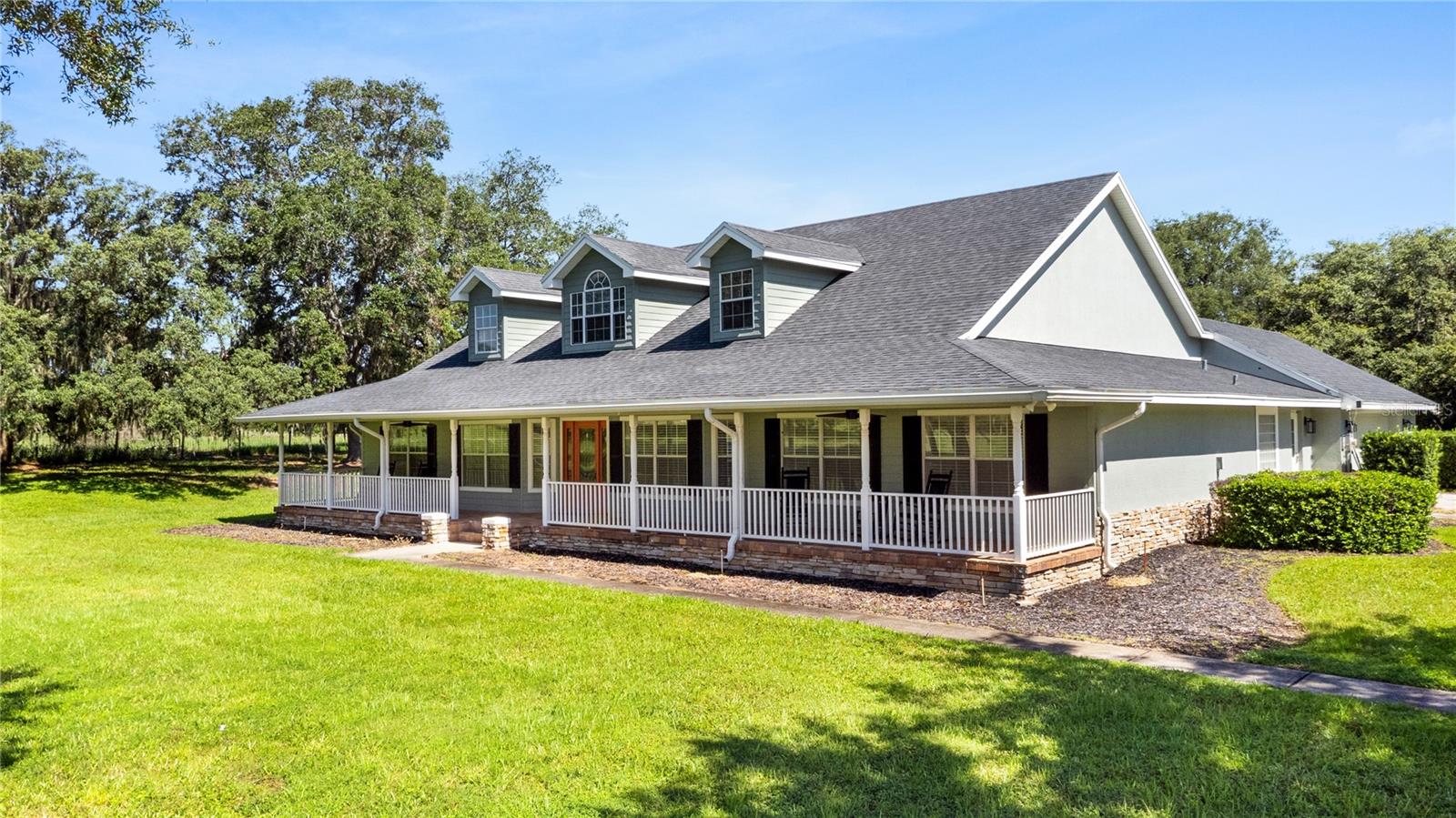 Welcome to your private country retreat! This custom-built 4-bedroom, 3-bathroom home with a dedicated office is nestled on nearly 6 acres of pristine, fully fenced land, offering a private country setting, just minutes from city conveniences. Ideally located just minutes from Haines City, Poinciana, and Winter Haven, with easy access to I-4 via Hwy 27, you'll enjoy peaceful rural living without sacrificing nearby amenities. As you enter through the PRIVATE GATED ENTRANCE and travel down the gravel drive, you'll immediately be drawn in  by the STUNNING FRONT PORCH stretching the entire width of the home—an inviting space perfect for morning coffee and enjoying the picturesque surroundings. Continue around the home to a  paved driveway and oversized two-car garage. An impressive 30' x 50' ALUMINUM WORKSHOP was added in 2023 and equipped with power, offering endless possibilities for storing vehicles, recreational equipment, tools, and more. Step inside to a welcoming foyer featuring beautiful wood-look tile flooring, elevated ceilings, and lovely views of the oversized pool. Crown molding throughout the living area adds a high-end appeal. The spacious living room is anchored by a outstanding STONE FIREPLACE, creating a warm and inviting focal point. Designed with both functionality and style in mind, the chef's kitchen boasts generous pantry storage, and abundant prep space topped off with custom cabinetry, granite countertops and stainless steel appliances. Two large islands, one that features a breakfast bar create a space for gathering and creating memories with family and friends. Just off the kitchen, the oversized laundry room doubles as a mudroom and offers a utility sink, folding station, ample cabinetry and storage, and convenient access to both the garage and driveway. Near the front of the home, a versatile flex space with pocket doors currently serves as an office but could easily function as a formal dining room, playroom, sitting room, or additional living area. The spacious primary suite is filled with natural light and offers a large walk-in closet and a private en-suite bathroom complete with a relaxing garden tub. On the opposite side of the home, a split-bedroom layout provides privacy for family and guests. Two generously sized guest bedrooms offer ample closet space, while the THIRD GUEST BEDROOM FEATURES ITS OWN EN-SUITE BATH with a walk-in shower and private access to the pool area—perfect for guests or multigenerational living. French doors lead to the true showpiece of the property, an incredible outdoor oasis overlooking the 5.96 acres of beautiful land. The OVERSIZED HEATED SWIMMING POOL features a waterslide, a rare find that tops off the ultimate backyard retreat. The electric pool heater was new in 2022. Surrounded by an expansive paver pool deck, there's plenty of space for entertaining, outdoor dining, grilling, or simply soaking in the peaceful scenery. Whether you're looking for room to roam, space for hobbies and equipment, or a private oasis, this exceptional property delivers it all. Roof 2019, Interior Paint 2024, Flooring 2024, pool heater 2022. Schedule your private showing today!