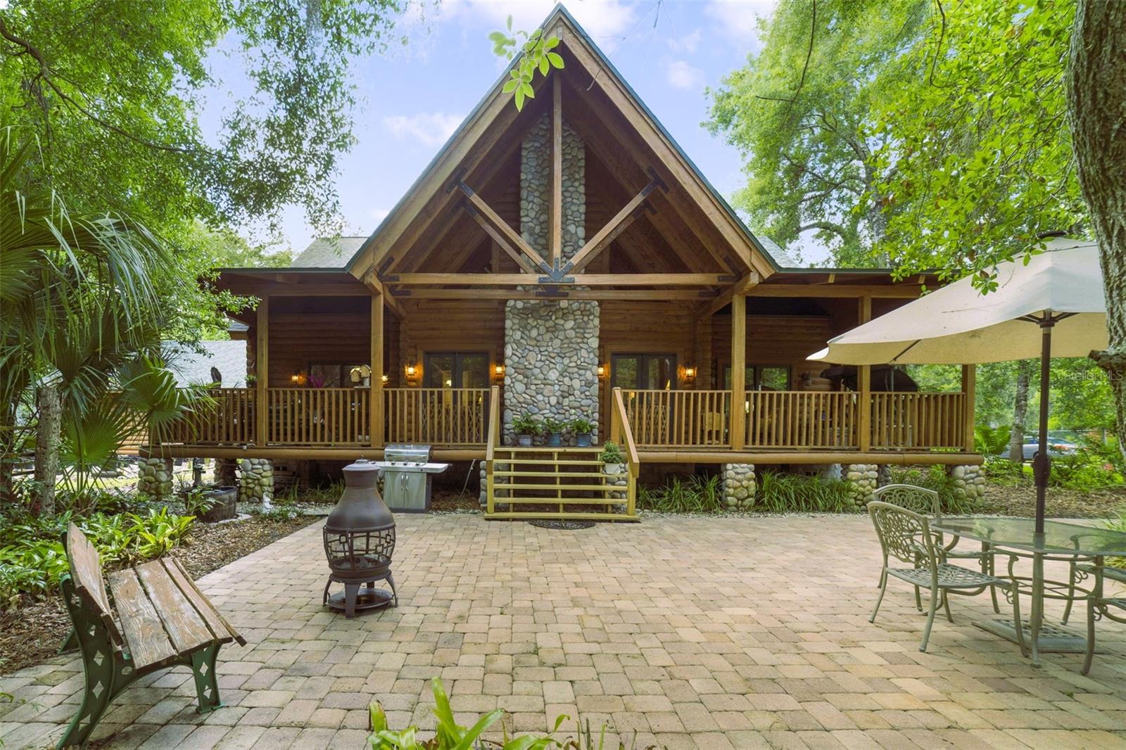 Tucked beneath the trees on a rare 1.4-acre homesite is an irreplaceable handcrafted cypress luxury estate, where mountain luxury meets the heart of Sanford Fl.  Using traditional techniques yet thoughtfully planned for Florida conditions. From the moment you arrive, the home feels more like a private Smoky Mountain retreat than a Florida residence, blending lodge-style craftsmanship with the convenience of being just minutes from charming downtown Sanford. Constructed with authentic 6-inch cypress logs using saddle-notch construction and lag screw fastening approximately every 18 inches, this remarkable home showcases an incredible level of craftsmanship and structural detail rarely found in today’s construction. Elevated stem wall and support pier foundation construction, soaring timber-framed ceilings, expansive covered porches, and substantial custom masonry detailing create a level of architectural character that is extraordinarily difficult and costly to reproduce. Inside, the dramatic great room immediately captures attention with soaring vaulted ceilings, exposed beams, spectacular floor-to-ceiling stone fireplace, and warm wood finishes throughout. Expansive DOUBLE PANE windows & multiple French doors flood the home with natural light while seamlessly connecting the interior spaces to the sprawling covered porches & peaceful wooded surroundings. The spacious kitchen overlooks the main gathering areas & offers abundant cabinetry, breakfast bar seating, stainless steel appliances, & the open-concept design perfectly suited for entertaining. Rich 3/4-inch tongue-and-groove red oak flooring flows throughout much of the home, complementing the natural warmth and timeless appeal of the custom construction. The primary suite offers a peaceful retreat atmosphere with direct porch access & serene natural views. Upstairs, a beautiful open catwalk overlooks the breathtaking great room below & leads to two extremely generous guest bedrooms and a full bath, creating the perfect setup for guests, home offices, hobby spaces, or private retreats. The upstairs bedrooms also feature additional storage areas, & throughout the home you will find an absolutely incredible amount of closet/storage rarely found in homes of any style. ADDED BONUS-DEEDED access to a private ski LAKE! Additional features include 2021 ROOF, DOUBLE-PANE windows & doors, CENTRAL VAC, GAS heat, gas appliances, outdoor gas grill connection, tankless water heater, irrigation system, security system & 2.5 GARAGE, WORKSHOP SPACE, FLOORED ATTIC. Outside, the setting is equally special. MASSIVE covered porches FRONT & BACK invite morning coffee, evening gatherings, & year-round enjoyment of the private surroundings. With NO HOA, there is ample room for boats, RVs, recreational toys, workshops, & future possibilities. The property also includes dedicated access to a private ski lake, offering an incredibly rare lifestyle opportunity!  This gorgeousness is located just minutes from charming brick-paved Downtown Sanford filled with historic buildings, incredible dining, boutiques, festivals, live entertainment, & endless local charm. Ride your golf cart to Downtown Sanford and enjoy sunsets along Lake Monroe, waterfront parks, shopping, world-class breweries, and amazing dining.  Excellent location with quick access to the 417, shopping, dining, and close proximity to Sanford International Airport, Lake Mary/Oviedo/Orlando. This gorgeous home is truly a one-of-a-kind gem!!