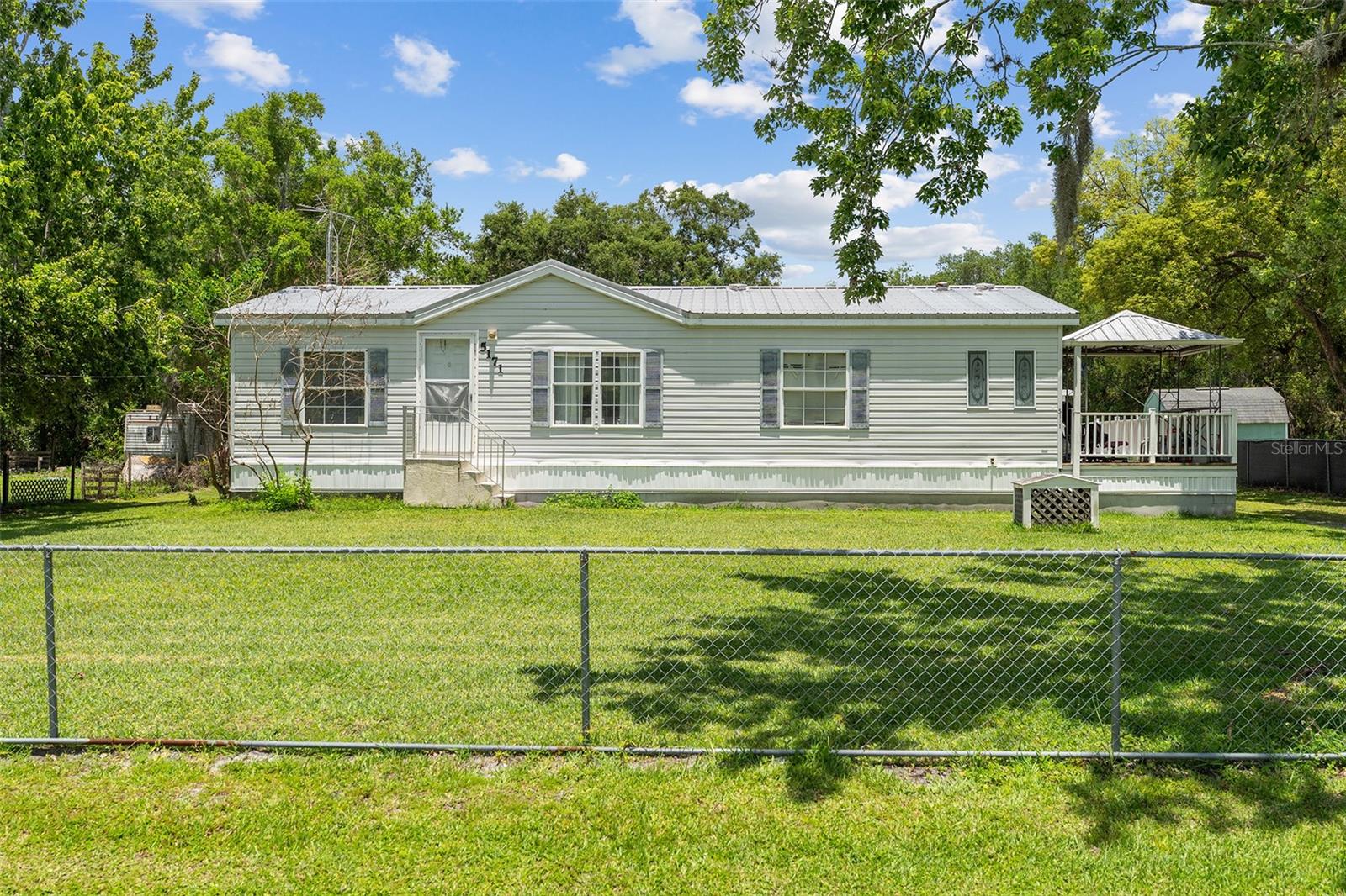 Welcome home to this charming 3-bedroom, 2-bath manufactured home situated on a spacious half-acre lot in a quiet and peaceful neighborhood. Step inside to discover an open-concept floor plan featuring laminate flooring throughout and a kitchen equipped with stainless steel appliances, making it perfect for everyday living and entertaining. Enjoy the outdoors from the expansive side and rear porch that nearly wraps around the entire home—ideal for family gatherings, weekend barbecues, or simply relaxing on cool Florida evenings. A storage shed in the backyard provides plenty of space for tools, equipment, and all your outdoor toys. Conveniently located just off Narcoossee Road, this property offers easy access to Lake Nona Medical City, Orlando International Airport, Disney attractions, beautiful beaches, shopping, dining, and more. Experience the perfect combination of peaceful country living and modern convenience!