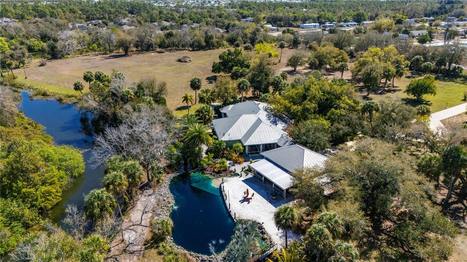 Welcome to your dream Waterfront Estate Home in Punta Gorda! This exceptional, 3.7-acre property features a Gated entrance, offering the perfect blend of luxury, privacy, and modern convenience. Owner Designed and Structural reinforced Concrete Built Estate Home, nestled in a private setting along Serene Alligator Creek, what a truly stunning Home. As you enter the front gates you will take in the beauty that the entire Estate is enveloped in carefully curated Florida-friendly landscaping, creating a true Florida paradise that follows through all the way to your dock on Alligator Creek. This Estate is very private and serene, but is wonderfully located close to shopping, dining, and quick access to I75 and Tamiami Trail. With just over 3,500 square feet of living space, this home is spacious and features a flexible floor plan to suit your needs and was designed for Income potential to function as an Airbnb along with offering Wedding and Memorial Venues, up to 35 times annually and 17 units of Real Estate Density.  This Beautiful Home Welcomes everyone from the Spacious Front Porch opening up to the Double Door entry, Crown Molding, Tray Ceilings, Transom Windows, Formal Living Space, Formal Dining Room, Executive Office, Family Room/Game Room, Large Kitchen with top of the line appliances, Center Island abundant Solid Wood Cabinetry, Breakfast Bar, Granite Countertops, Some Furniture included, Oversized Laundry Room with additional Storage, Split Floor Plan with Private Primary Suite with Split vanities, Jetted Soaking Tub, Separate Walk-in Shower, Large His and Her’s walk-in closets, 3 Guest Rooms, 3 Full Baths and an outside Half-Bath and separate heated outdoor Shower,  2 Screened Rear Patios giving way to More Living Space to take in the Quiet and Graceful setting. Car enthusiasts will appreciate the Detached 38x30ft AC Four-plus car garage with 3 overhead electric doors, providing ample space for vehicles and storage, along with an additional 30x15ft storage room with 2 overhead doors, a 30x15 covered patio/entertainment area, and a person Hot Springs Hot Tub.  Enjoy the Tennessee Flagstone walkways, an 80,000 galloon contained Natural Outside Lagoon/Pond with concrete bottom and walk-in Sandy Beach area, unwind in sounds of the Custom Rock Fountains, Waterfalls, plus a Koi Pond these Water features are accented throughout the backyard, perfect for enjoying the Florida sunshine offering a serene retreat for relaxation and rejuvenation. This Estate combines attention to detail, style, function, and flexibility in a Private, Expansive setting. The two adjacent 5 Acre parcels are available separately, giving you an opportunity to expand, also the Furniture along with Game Room equipment is negotiable. Enjoy all the amenities that Punta Gorda has to offer, such as fishing, boating, Charlotte Harbor, golf, pickleball, tennis, bike and walk paths, dining, live entertainment, shopping and Historical Downtown Punta Gorda. Also take a Drive to award-winning beaches such as Boca Grande, Englewood Beach, Manasota Key just to name a few. We Invite you for Tour of this Exceptional Estate Home, let's make this yours!