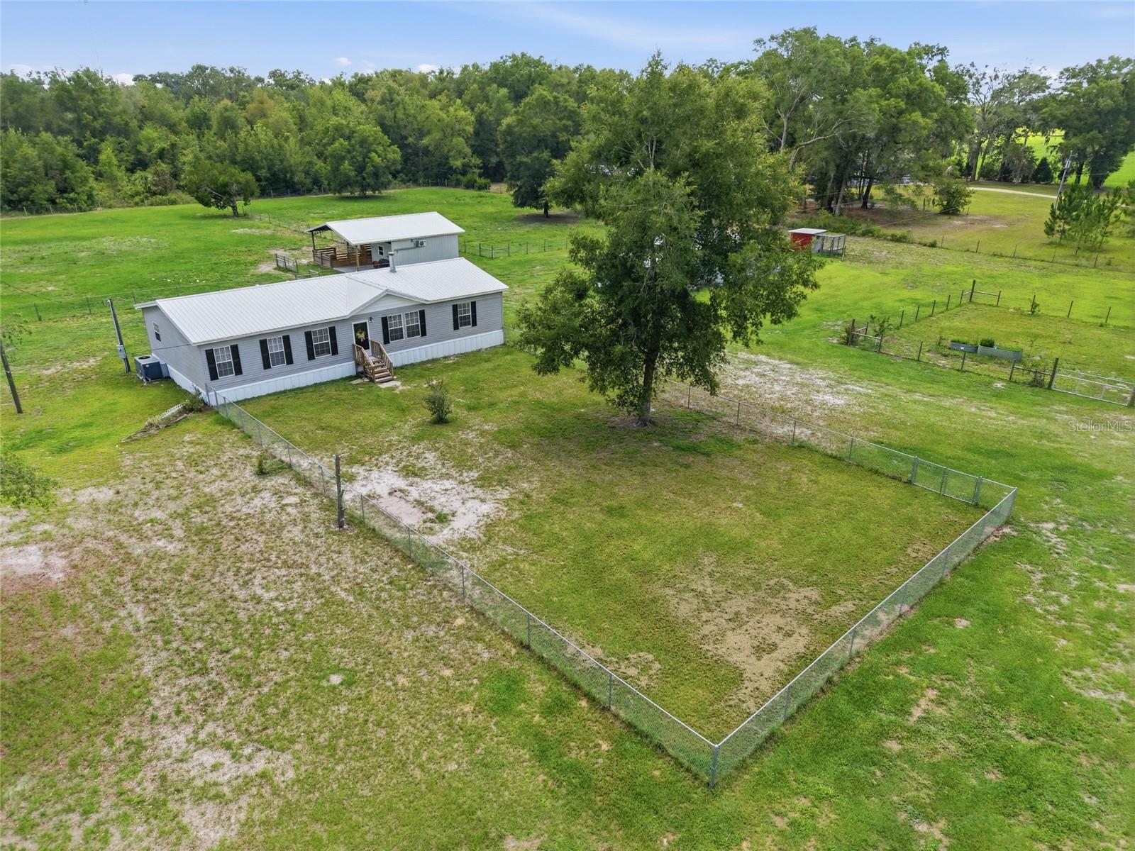 BELL FLORIDA HORSE PROPERTY ON 5 ACRES IN GILCHRIST COUNTY. Located just outside the charming town of Bell, Florida, this fully fenced 5-acre MINI FARM is set up for horses, homesteading, and country living. Conveniently located in Gilchrist County and only a few miles from the Suwannee River, this well-maintained property offers a 3-bedroom, 2-bath home along with excellent equestrian and agricultural improvements. The horse barn features three stalls with a paved aisle and stalls that lead directly to two paddocks located behind the barn. An air-conditioned tack room provides comfortable storage for saddles, tack, and equipment. Whether you're a horse owner, hobby farmer, or simply looking for room to spread out, this property is ready to go or to further customize to your preference. Additional outbuildings include a 24x24 fully enclosed workshop with an attached 12-foot overhang, providing plenty of space for equipment storage, projects, or a home-based business. A separate 20x20 metal carport offers additional covered parking for vehicles, tractors, trailers, or farm equipment. Homesteaders will appreciate the charming chicken coop and the fully fenced garden complete with irrigation and ready for planting. Inside, the home offers a functional split-bedroom floor plan with an oversized primary suite featuring two walk-in closets and an adjoining bonus room ideal for a home office, nursery, exercise room, or private sitting area. The spacious kitchen includes stainless steel appliances, abundant cabinetry, and plenty of workspace for meal preparation and entertaining. The cozy living room is highlighted by a wood-burning fireplace, creating a warm and inviting gathering space during cooler months. Additional features include wiring for a generator or RV hookup, a metal roof installed in 2016, and a large rear deck overlooking the fenced pasture and surrounding acreage. If you're searching for a North Florida horse property, mini farm, or country home with acreage in Gilchrist County, this property offers the improvements, functionality, and RURAL LIFESTYLE buyers are looking for.