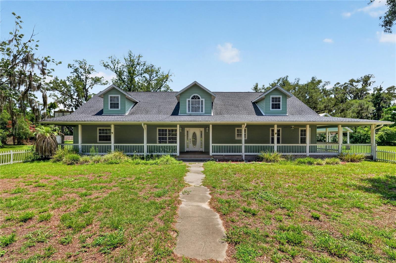 Secluded Country Treasure Minutes from Downtown Trenton. Tucked away down a long, scenic driveway and framed by majestic, mature oak trees, this expansive country-style estate offers a rare blend of peaceful seclusion and modern convenience just minutes from downtown Trenton. The property stands as a true private sanctuary, welcoming visitors with a classic wrap-around front porch that invites quiet moments of relaxation. Designed to seamlessly accommodate rural living, the estate is fully fenced and cross-fenced, complete with dedicated water lines running out to a pasture perfectly suited for horses or cattle. Approaching the home reveals a massive carport that provides ample space for parking and storage beneath the shade of the stunning landscape. Stepping inside, the front door opens into a bright and airy living space defined by soaring high ceilings and an open-concept floor plan. The heart of the main floor features a generous kitchen centered around a large island, which overlooks the main family room and stands ready for custom modern updates. Designed with privacy in mind, the thoughtful split floor plan ensures separate living zones. One wing anchors two comfortable bedrooms connected by a shared Jack-and-Jill bathroom, while a large, versatile den located just down the hall easily functions as a private home office, media room, or fourth bedroom. On the opposite side of the home, the primary suite serves as an expansive retreat, boasting two walk-in closets and direct access to a tranquil screened porch where you can unwind. Adding incredible value and versatility to this estate is the upstairs level, which functions as its own entirely private apartment. Accessible via a private entrance, this separate living space comes fully equipped with its own kitchen, a full bathroom, and a remarkably large living area. This exceptional feature makes the home ideal for multi-generational living, an independent guest suite, or a potential rental opportunity, all while maintaining the utmost privacy for the main household below.