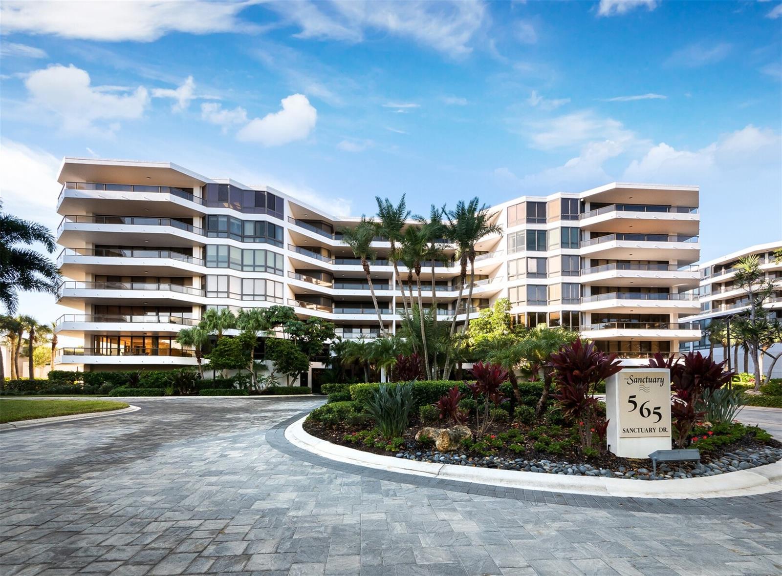 Nestled behind the exclusive gates of the Longboat Key Club, The Sanctuary enjoys an enviable location along a pristine stretch of Longboat Key’s Gulf beach. This exceptionally renovated 3BR, 3BA residence with nearly 2,400 square feet of living space is simply stunning. This corner residence features a thoughtful split-bedroom layout, elegant finishes and floor to ceiling high-impact glass leading to an open, wraparound terrace, where views of tropical palms and lush green space set the tone for outdoor dining, entertaining or a peaceful retreat. Inside, neutral tones with tasteful accents combine with walls of glass to create a bright, flowing ambiance. Trey ceilings, engineered hardwood flooring and tile in the baths add refined detail. The oversized kitchen is exceptional, with colorful cabinetry, stone countertops, and a large island with breakfast bar seating that opens seamlessly to the living room. Residents of the Sanctuary enjoy a recreational room, 24hr security guard, heated swimming pool, 2 Har-Tru tennis courts, and on-site management. Just steps away, the exclusive Longboat Key Club offers championship golf, a deep-water marina, a world-class spa, a private beach club, and fine dining, providing an unparalleled coastal lifestyle.
