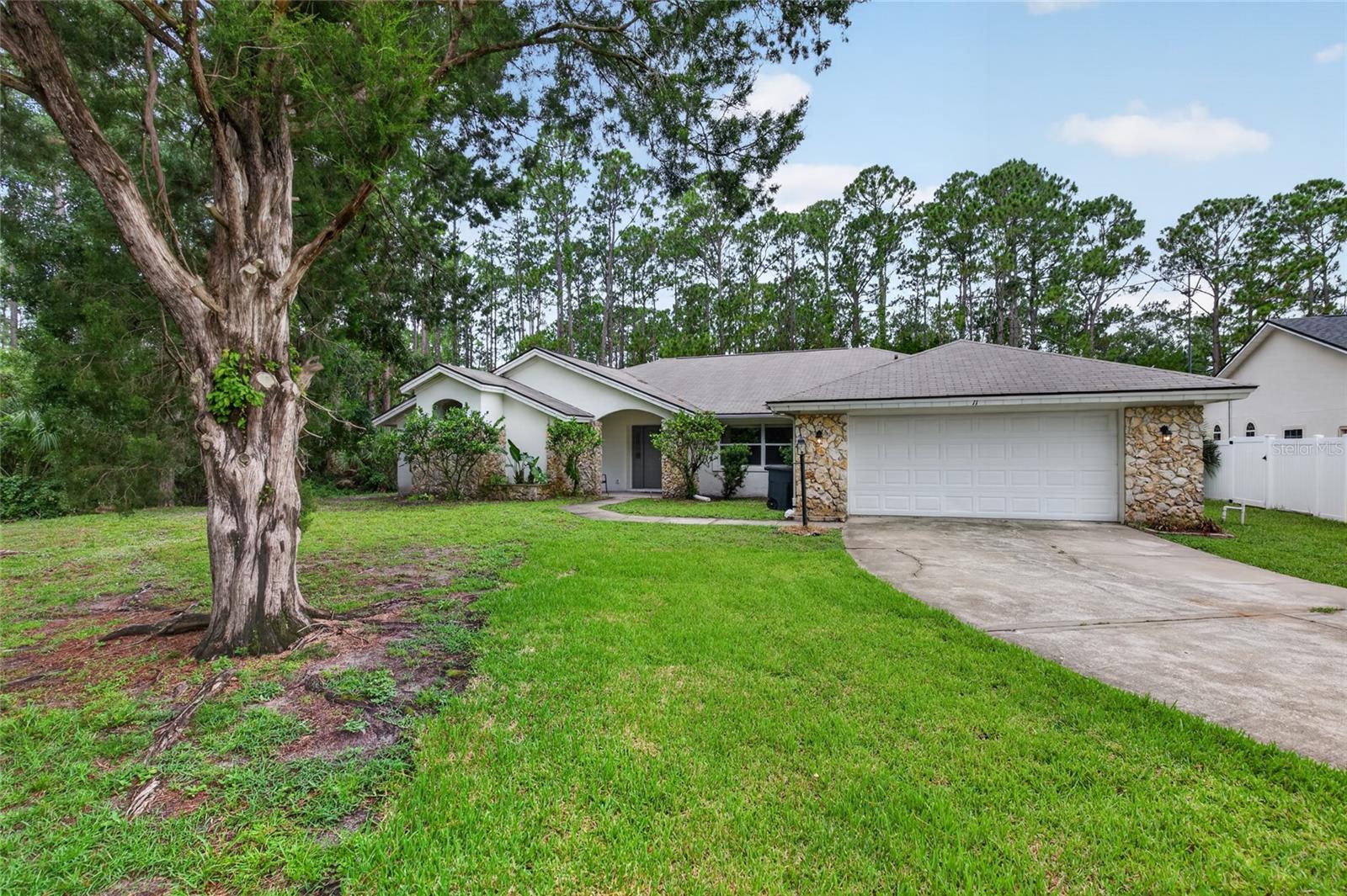 Welcome to 11 Walnut Place, a spacious 5-bedroom, 3-full-bath home offering 2,909 square feet on a desirable corner lot in the heart of Palm Coast. This well-maintained residence features luxury vinyl plank flooring throughout the main living areas, fresh neutral finishes, and a flexible floor plan designed for both everyday living and entertaining. The expansive great room with fireplace serves as the centerpiece of the home and flows seamlessly into the kitchen and dining areas. The kitchen offers abundant cabinetry, generous counter space, stainless steel appliances, a breakfast bar, and a convenient pass-through window to the screened lanai. The primary suite provides a relaxing retreat with private lanai access and an en-suite bath featuring dual vanities, a soaking tub, and separate shower. A separate bedroom with its own adjacent full bath is situated on the opposite side of the home, creating an ideal setup for multi-generational living, extended family, guests, or added privacy. Three additional bedrooms offer flexibility for family, visitors, or a home office. The large screened lanai expands the living area and creates the perfect setting for relaxing or entertaining. Conveniently located near shopping, dining, schools, parks, and major roadways, this property offers exceptional space, functionality, and value in a central Palm Coast location.