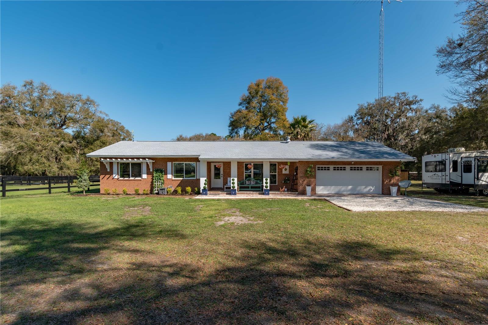 This fabalous property is back on the market due to no fault of it's own.  Maybe it was waiting on you.  Ideally located between both Ocala and Gainesville, this charming 5-acre mini-farm is thoughtfully designed and recently updated. The 3-bedroom, 2-bath home welcomes you with an open floor plan, where abundant natural light highlights the many upgrades throughout. The kitchen is well-equipped with granite counters, a center island, stainless steel appliances including a gas range, and a tiled backsplash— a perfect blend of function and style. Ceramic wood-look tile flooring flows throughout the home, complementing the modern farmhouse aesthetic. The primary suite features a private en-suite bath with dual sinks and a tiled shower for added convenience. Both the covered front porch and expanded rear porch offer cedar plank tongue-and-groove ceilings, with the rear porch further enhanced by a wooden deck extension that provides even more space to enjoy the peaceful views. Outside, the property is well-suited for horses or other livestock, with four cross-fenced paddocks ready for use. An RV hookup with septic is in place, offering even more options for your RV or potential guests. Whether you’re looking for a turnkey mini-farm or simply a serene country retreat, this property offers endless possibilities in a prime North Central Florida location.