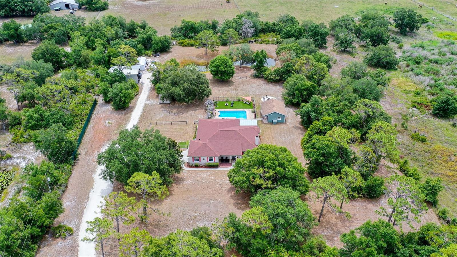 Private, gated, and set on 5 fully fenced acres, this country pool home offers the perfect blend of privacy, recreation, and everyday comfort. Designed for those who value space, flexibility, and an active outdoor lifestyle, this property is more than a home—it's a place where memories are made. 
The main home offers 4 bedrooms, including an oversized primary suite with a large walk-in closet and Jacuzzi tub. Inside, you'll find engineered hardwood flooring throughout the main living areas, laminate flooring in the bedrooms, luxury vinyl flooring in the bathrooms, and stainless steel appliances. The detached pool house provides an additional 504 square feet of air-conditioned space beyond the home's reported living area. A new roof and HVAC system were installed in 2022, providing added peace of mind for years to come. 
Step outside and discover an entertainer's dream. An oversized pool, screened porch, covered outdoor gathering area, and detached air-conditioned pool house with a full bathroom create the ideal setting for year-round Florida living. Host family movie nights under the stars, gather around the fire pit with friends, or spend quiet evenings fishing from the dock in your private stocked pond. The expansive grounds provide plenty of room for recreation, relaxation, and natural beauty, complete with seasonal wild blackberries scattered throughout the property. 
For hobbyists, outdoor enthusiasts, and those with recreational vehicles, the property includes a large barn designed for RV and boat storage with a 30-amp hookup and separate electric meter, along with a separate powered workshop offering exceptional versatility. Whether you're storing boats, RVs, equipment, or pursuing your favorite projects, this property provides the space and freedom to do it all. With no HOA, you'll enjoy the flexibility to make the most of your property without restrictive community regulations