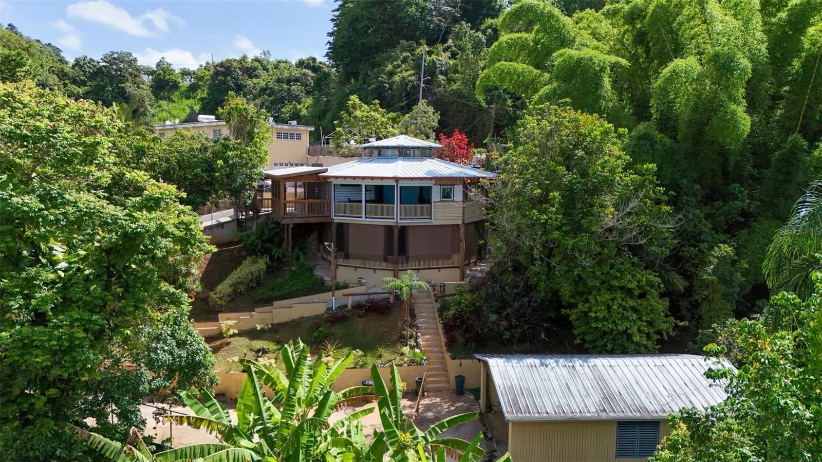 Nestled in the exclusive gated community of Villas de Monte Verde in Ponce, this beautiful residence offers privacy, breathtaking panoramic views, and a peaceful mountain setting. Built with treated wood, the home combines warmth, character, and functionality in a unique natural environment.

The property features a 3,930-square-meter lot, providing ample outdoor space with endless possibilities for relaxation or future enhancements. It is equipped with a 14 kW gas-powered generator and a 1,450-gallon water cistern, offering added convenience and peace of mind.

Whether you’re looking for a primary residence, a vacation retreat, or a serene escape surrounded by nature, this property delivers exceptional views, comfort, and the security of a controlled-access community.