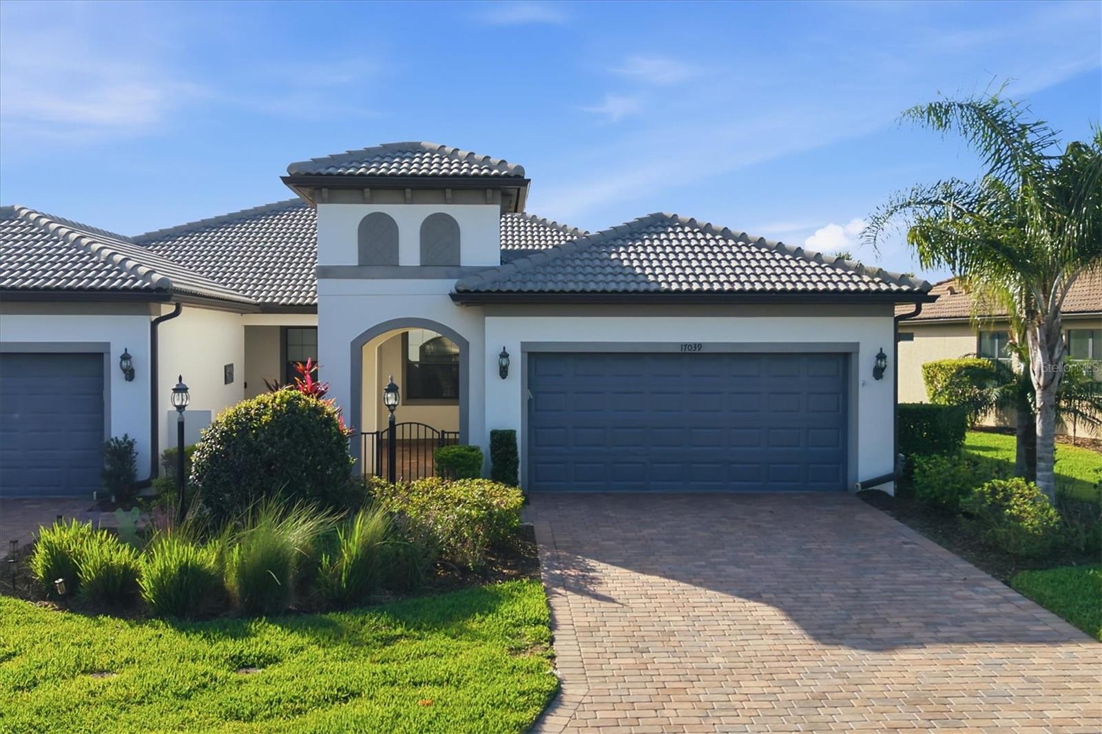 Virtually Staged. NOW THE LOWEST PRICED HOME IN Del Webb Lakewood Ranch! AN INCREDIBLE OPPORTUNITY FOR BUYERS LOOKING FOR THE BEST VALUE. This pristine villa with with a thoughtful design, and an unbeatable location come together in perfect harmony.  Just a short stroll or golf cart ride to the amenity center, this beautifully maintained villa offers the ideal blend of privacy, comfort, and connection.   Featuring  a flexible floor plan with 2 bedrooms plus a den, complete with solid French doors and a generous alcove perfect for a third bedroom, office, or hobby space.  From the moment you arrive, the curb appeal sets the tone with a paver driveway and walkway leading to a charming gated courtyard - and an inviting and private entry that feels both elegant and welcoming. Inside, the home shines with immaculate, like-new condition and newer waterproof laminate flooring flowing seamlessly throughout.  The open-concept design features an extended kitchen, dining, and living space - perfectly arranged for easy everyday living and effortless entertaining.  The kitchen overlooks the entire main living area, keeping everything connected and bright.  Sliding glass doors lead to a brick paver, screened-in lanai, offering a peaceful outdoor retreat with a glimpse of the lake and a sense of privacy.  The primary suite, privately situated at the rear of the home, offers a quiet retreat with an en-suite bath featuring dual vanities, granite countertops, a glass-enclosed shower with dual showerheads, and a spacious walk-in closet. Guests will appreciate the secondary bedroom and full bath located at the front of the home, ideal for visiting family and friends.  Additional highlights include: Generac full house generator, Culligan water purification and softener systems, hurricane protection panels, freshly painted garage floor. exceptionally clean, move-in-ready condition. Residents of Del Webb Lakewood Ranch enjoy a vibrant lifestyle, activities director, resort-style amenities including a stunning pool, state-of-the-art fitness center, pickleball and tennis, social clubs, dining, and endless opportunities to connect or simply relax.  All of this within Lakewood Ranch, the nation's top-ranked multi-generational community, known for its lifestyle, beauty, and convenience. Just a short ride from the renowned UTC shopping and dining , downtown Sarasota with it's vibrant culture and arts, and award-winning gulf beaches.