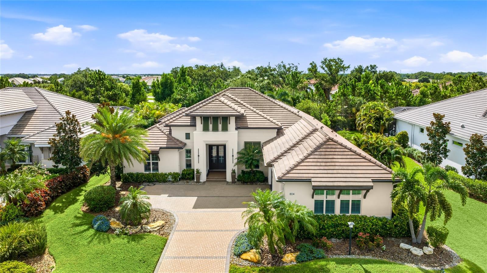 Welcome to one of Lakehouse Cove at Waterside's most distinguished residences, a former Arthur Rutenberg model home conceived as the builder's finest expression, heavily upgraded, and gently enjoyed as a second home ever since. Offered fully furnished, down to the designer interiors and Ebel outdoor collection, this is a rare turnkey opportunity in one of Lakewood Ranch's most coveted enclaves. Beyond the paver motor court and glass double entry, 3,217 square feet unfold with the composure of a home designed to be shown. Engineered hardwood floors run beneath layered tray ceilings inlaid with wood, and the great room dissolves through walls of glass, including a zero-corner slider, into the outdoor living beyond. The kitchen is appointed with quartz surfaces, gas cooking, a wine refrigerator, and a built-in pantry, while a vaulted bonus room with decorative beams and a private office offer living space of real presence. The owner's retreat is quietly indulgent, with a feature ceiling, electric blackout blinds, direct pool access, and custom fitted closets, and its bath centers on a freestanding soaking tub, dual quartz vanities, and a walk-through shower with three shower heads. An ensuite guest room, a third bedroom with fitted closets, and an oversized laundry with walk-in storage complete the plan. Outdoor living rivals the finest resorts. Beneath tongue-and-groove ceilings, the lanai centers on a custom entertainment wall with a feature fireplace, television, and sound bar, while the heated saltwater pool and spa offer a sun shelf with in-water loungers. An outdoor kitchen with a Fire Magic grill stands ready for entertaining, and a clear-view screen frames a fully fenced garden backed by a pocket park, ensuring total privacy. A Generac whole home generator on a weekly-tested service agreement, hurricane impact windows and doors, a 2024 A/C with a new 2026 Trane air handler under warranty, a tankless water heater, water softener, and Control4 smart home technology make ownership effortless. Life at Lakehouse Cove centers on a lakefront clubhouse overlooking Kingfisher Lake, with a resort-style pool and spa, fitness center, fire pit, pickleball and bocce courts, an events lawn, playground, and two dog parks, plus a community boathouse with kayak launch and storage. Walk or bike to Waterside Place without crossing a major road, or ride the community water taxi across the lake to Sarasota's only waterfront town center, home to al fresco dining, boutique shopping, Ranch Night Wednesdays, and the Sunday farmers market voted number one in the country. Downtown Sarasota, UTC, and the Gulf beaches are an easy drive.