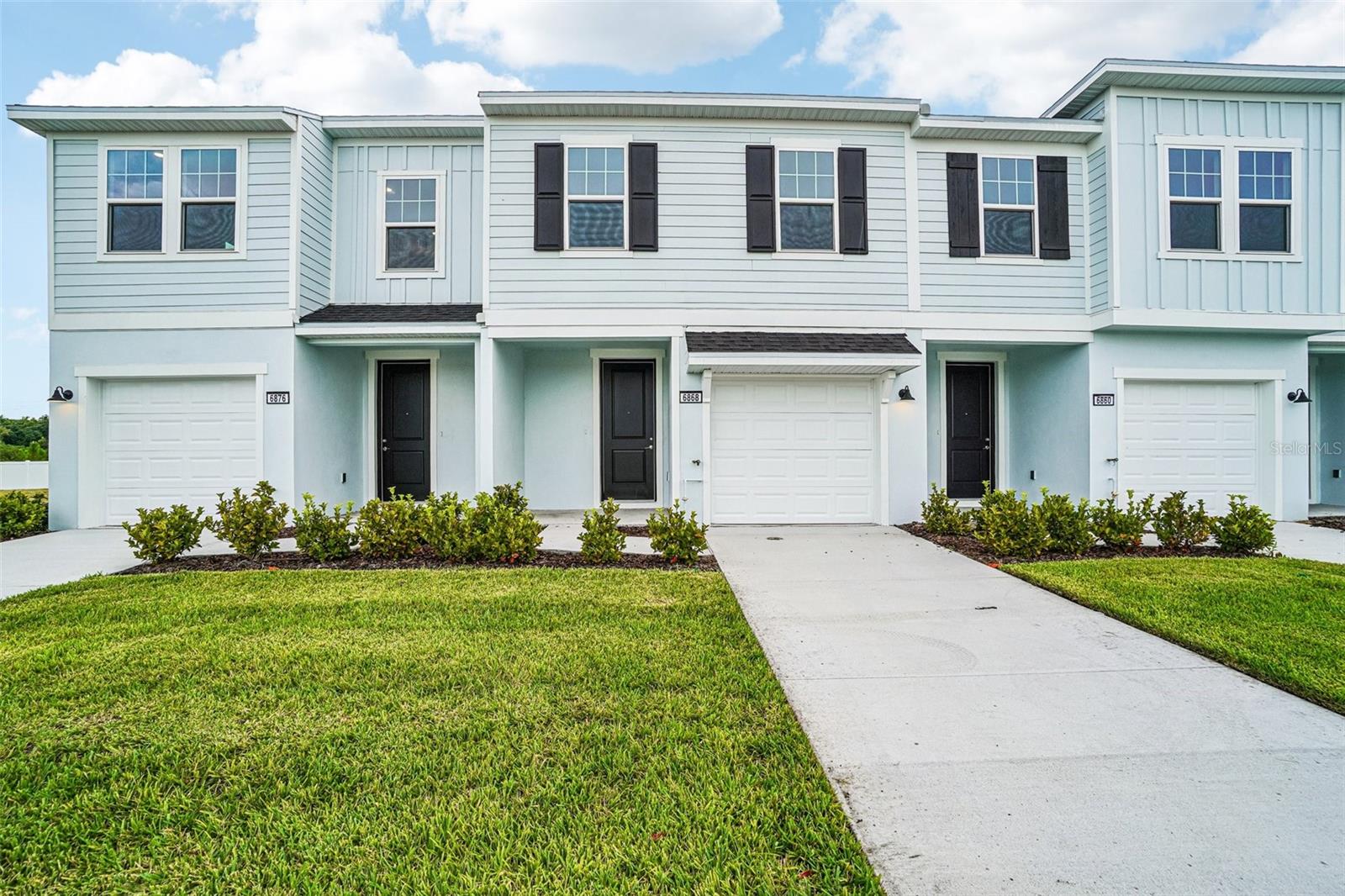 The Leila plan is a two-level townhome featuring a 1-car garage and covered lanai. The main level offers an open living area with a spacious family room and a rear kitchen with a large island suitable for meal preparation and entertaining. Some layouts provide a centrally located kitchen with rear family room and lanai access. The second floor includes the primary suite with a walk-in closet and en-suite bathroom featuring a dual-sink vanity and walk-in shower. Two additional bedrooms and a conveniently located laundry room complete the upper level. Interior finishes include luxury vinyl plank flooring throughout the main living areas and stairs, with ceramic tile in the bathrooms. The backyard may be fenced with restrictions. Community amenities include a pool, playground, and cabana.