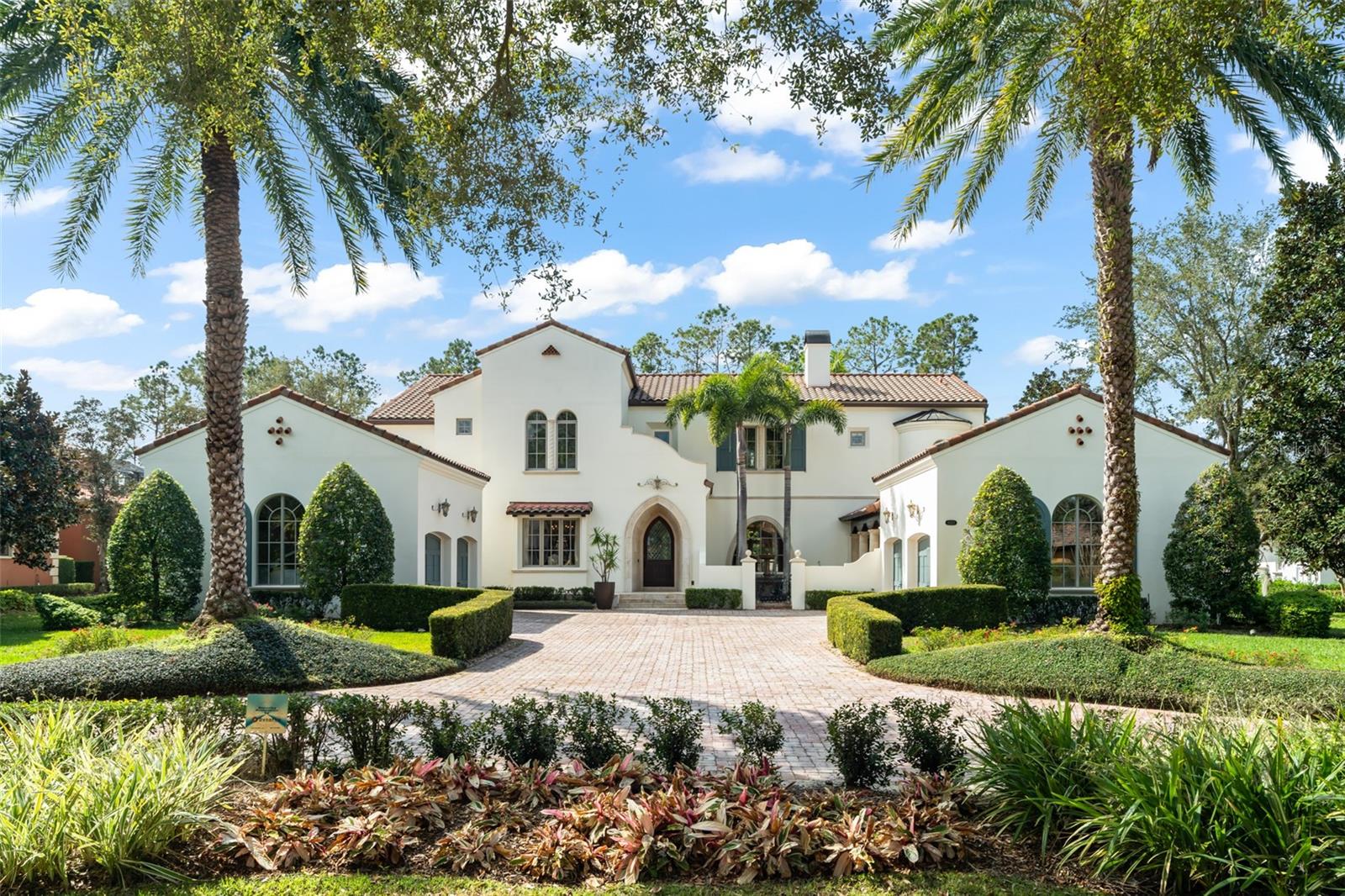 Elegance defined behind the guarded gates of the Reserve at Lake Butler Sound. Welcome to “Evening Sun:” a stunningly beautiful residence that pays homage to Italian style and opulence mixed with the poise and splendor of an idyllic cathedral. Be impressed with graceful sophistication upon entry of stone flooring, rich wood millwork, iron railings and a dramatic winding staircase. Formal spaces are luxurious and inviting and include a generous-sized dining room with adjacent wine room and refrigeration, sumptuous living room with stone two-sided fireplace, executive-style den with elevator and courtyard access. A refined family room with wood flooring, stone gas fireplace, and floor to ceiling drapes offer grand accents and French doors lead to a backyard oasis. Outside, manicured grounds frame a mammoth resort-style pool with hot tub, rock waterfall features, alfresco dining space with fireplace and TV, Travertine decking, and an impressive newly-built showcase cabana with motorized invisible screens, BBQ grill and full kitchen, and extra spaces for outdoor entertaining. The interior gourmet kitchen includes dual refrigerators, dual dishwashers, 6-burner gas cooktop with griddle, pot filler, walk-in hidden pantry, stone counters, double sinks, and bar seating. A stately corridor leads to a primary retreat that is tranquil and dignified with classic and tasteful design with a lancet window, decorative stone and wood inlays, faux glaze touches, jetted tub, separate water closet with toilet and bidet, walk-in tiled shower with double heads, and generous closet room. Upstairs are four additional bedrooms, all ensuite, and a just-reimagined game room with wet bar, elevator, built-ins, and French doors leading to an upstairs loggia for additional outdoor space. Other extras include: two workstations, 7-zone whole home audio system with smart phone technology, ethernet jacks in every room and pool cabana, “hard wired” smart TVs and video devices, water heater recirculation pumps, both tankless and hot water heaters, two separate 240V circuits for electric vehicle charging, and four car garage with circular driveway. Walking distance to Windermere Prep and offering easy access to shopping, restaurants, theme parks, and downtown Windermere.