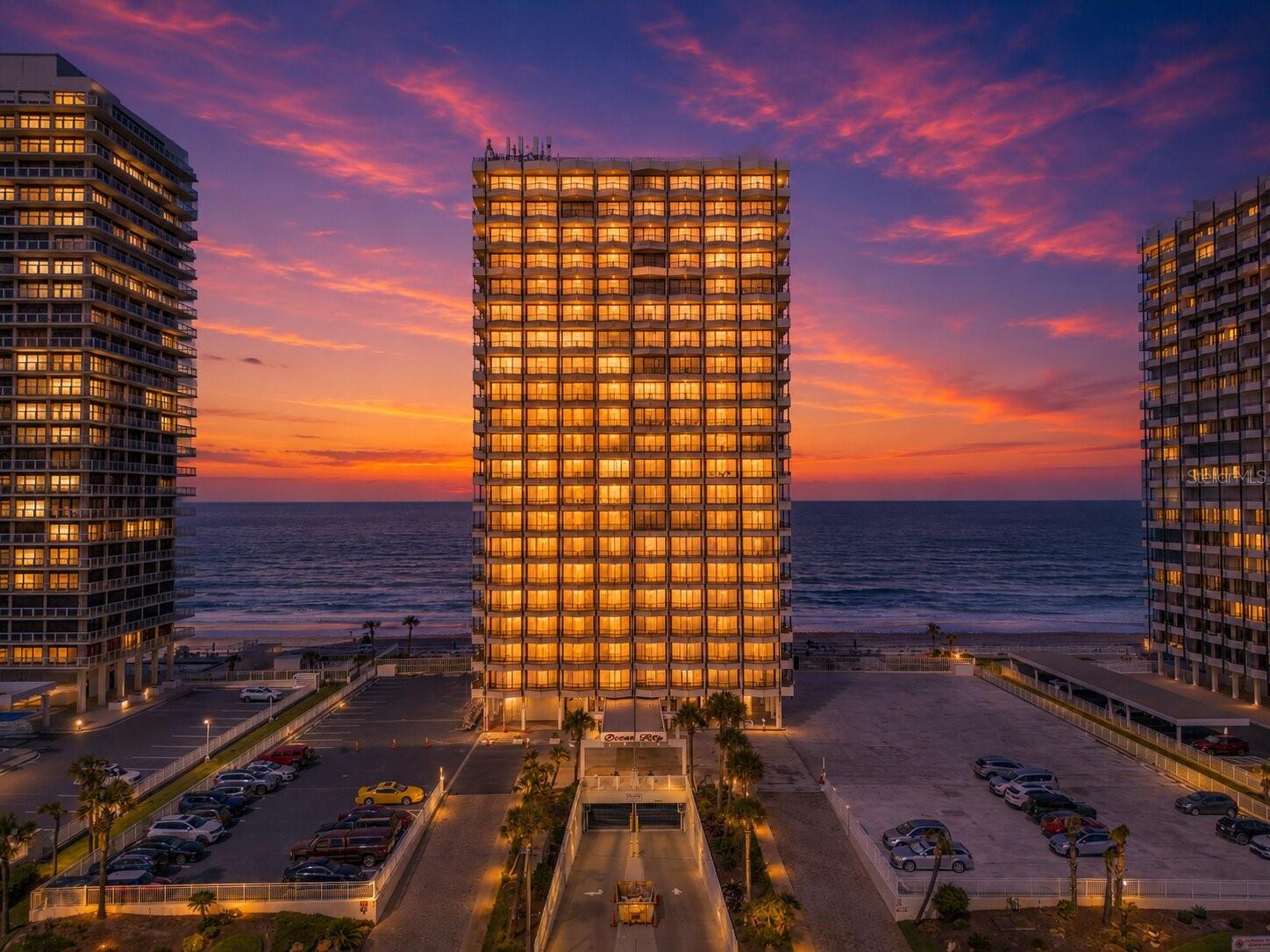 Perched high above the Atlantic on the 21st floor, this breathtaking south-west facing two-bedroom, two-bathroom Ocean Ritz penthouse captures the best of Florida’s sunshine and delivers the ultimate luxury coastal lifestyle. Positioned as one of the building’s most desirable sun-drenched residences, this southwest exposure fills the home with warm natural light from morning through sunset, enhancing its already striking oceanfront presence. Spanning 1,360 square feet of ultra-modern design, the residence welcomes you with a dramatic open floor plan framed by endless, panoramic ocean views. A new roof completed in 2024 adds peace of mind to this exceptional offering, reinforcing the quality and care behind the building. At the heart of the home is a sleek, chef-inspired kitchen outfitted with premium stainless steel appliances, solid surface counters, and a vibrant breakfast bar that flows seamlessly into the dining and living spaces. The entire residence is being sold fully furnished for immediate move-in, featuring stylish new furniture throughout, including beds, mattresses, and TVs, allowing you to step right into a turnkey coastal retreat without lifting a finger. Double down on the wow factor by stepping onto the crown jewel of the property: a jaw-dropping 65-foot wraparound balcony designed for unforgettable sunrises, golden-hour gatherings, and effortless entertaining with the ocean as your backdrop. The primary suite is a private sanctuary, highlighted by an exclusive three-panel sliding glass door that invites the sea breeze directly to your bedside, along with an ensuite bath featuring a generous vanity and a walk-in shower. Guests will enjoy equal comfort in the spacious second bedroom, complete with a dual-sink bathroom and its own walk-in shower. Life at the Ocean Ritz feels like a permanent vacation, offering a grand lobby, an expansive social room with a caterer’s kitchen, an oceanfront heated pool, and a park-like outdoor oasis with tables and gas grills, all supported by effortless on-site management. Centrally located in a highly coveted beachside destination, you are moments from Daytona’s top restaurants, pristine beaches, premier shopping, and major highways. Turn the key, settle into your fully furnished oceanfront escape, and step straight into penthouse living at its finest.