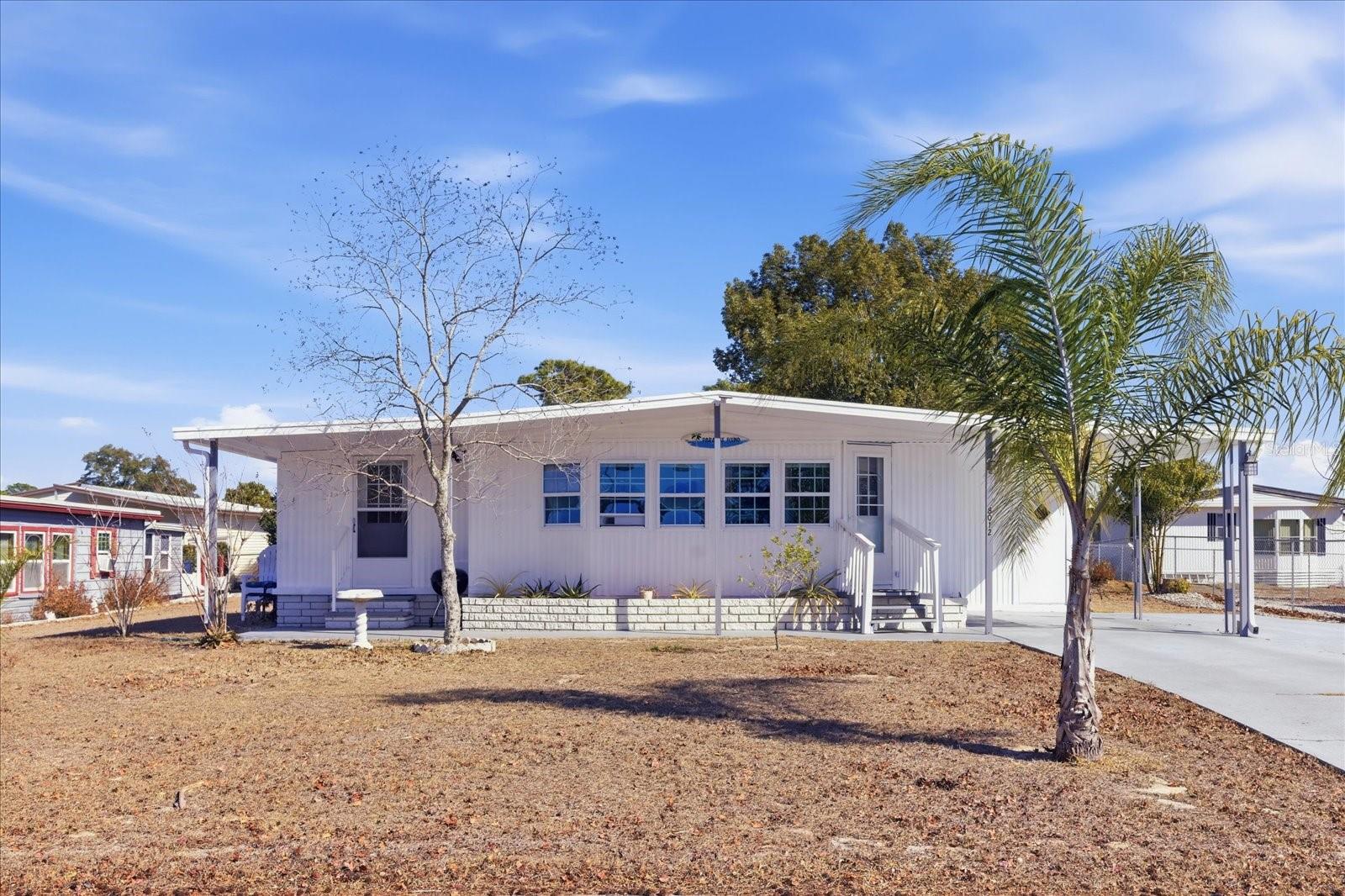 You own the land! NO LOT RENT. Located in the gated 55+ Brookridge golf community, this well-maintained home offers land ownership with no lot rent and low HOA fees. The open floor plan features 2 bedrooms and 2 full bathrooms, a bright living and dining area filled with lots of natural light, and a generously sized kitchen with abundant cabinetry and an updated backsplash. Recent improvements include a TPO roof and vapor barrier installed in (2019), a newer electrical panel (2024), an updated hall bathroom (2024) with a deep tub and updated backsplash, new flooring, a newer washer and dryer, and a freshly painted exterior in (2025). An enclosed sunroom, currently used for storage, adds approximately 140 square feet along with additional storage in the inside washer and dryer room. A double driveway provides convenient guest parking easily fitting 3 vehicles. Residents enjoy access to golf along with a variety of community amenities including tennis, shuffleboard, and a heated pool with much more to do in the highly desired Brookridge community.