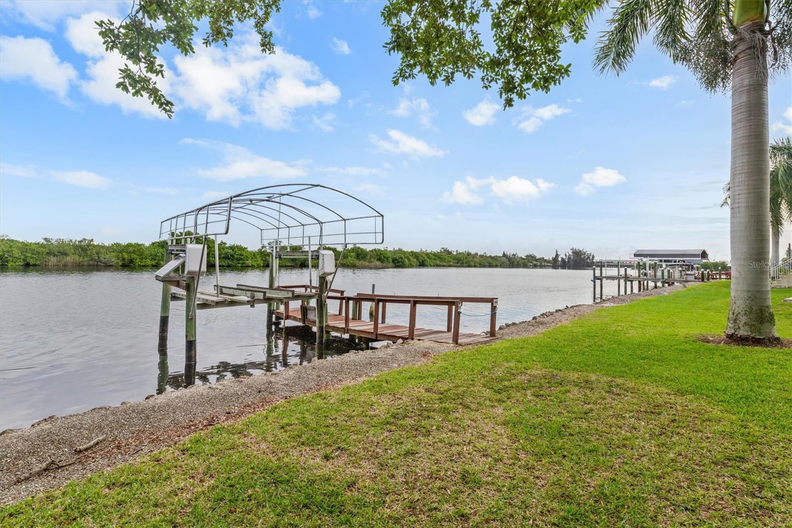 Welcome to this furnished, move-in ready 2-bedroom, 2-bath waterfront home with private dock and boat lift in the highly desirable 55+ Lazy Lagoon community. Built in 2005 and elevated 5 feet higher for added peace of mind, this well-maintained 1,152-square-foot home combines comfort, convenience, and waterfront charm. Major updates include a newer roof installed in 2023, a brand-new AC system and hot water heater in 2026, giving confidence that the most important improvements have already been completed. Step inside and enjoy beautiful luxury vinyl flooring that flows throughout the entire home, complemented by elegant crown molding in every room. The spacious great room combines the living and dining areas into an inviting space that feels bright and open. Sliding glass doors lead to a covered deck overlooking the canal, creating the perfect spot to enjoy morning coffee, evening sunsets, or simply take in the peaceful waterfront views. The updated kitchen is both functional and attractive, featuring wood cabinetry, generous countertop space, a refrigerator, stove, microwave, and a new dishwasher installed in 2026. The primary bedroom offers comfort and style with a ceiling fan and a private bathroom featuring a walk-in shower with glass doors. The guest bedroom also includes a ceiling fan, while the guest bathroom offers a convenient tub and shower combination. A laundry closet with a washer and dryer adds everyday convenience. Outside, new concrete steps provide easy access to the side and backyard areas. The two-car carport includes a secure storage shed that is perfect for tools, beach gear, fishing equipment, or seasonal items. Bikes in shed stay! Lazy Lagoon is more than just a neighborhood—it is a vibrant waterfront community packed with amenities. Residents enjoy a private road, additional guest parking, and an exclusive boat ramp for easy access to Shell Creek. Fishing enthusiasts will appreciate the convenient fish cleaning station, while the impressive 2,000-square-foot clubhouse with a commercial kitchen serves as the center for community events and gatherings throughout the year. Shuffleboard courts, a billiards room, and a pool room provide plenty of opportunities for recreation and entertainment. Boating enthusiasts will love the community’s more than 2,000 feet of maintained shoreline, along with a private secured compound for boat and trailer storage available for a small annual fee. The location puts you just minutes from Punta Gorda, offering outstanding dining, shopping, waterfront parks, and entertainment options. Don’t miss this opportunity to enjoy peaceful waterfront living in a well-maintained, amenity-rich community. Schedule your private tour today and discover everything this exceptional home and Lazy Lagoon have to offer.
