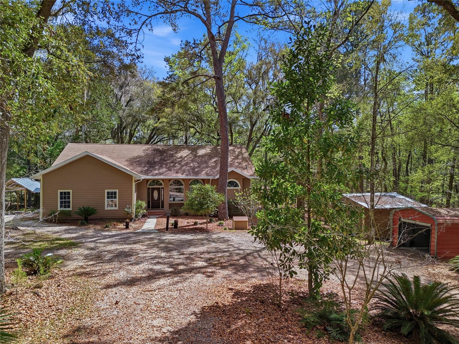 Welcome to this charming 3-bedroom, 2-bath home located in the desirable Bellamy Road Estates, situated off one of the most beautiful roads in the area. From the moment you arrive, the adorable front porch invites you to slow down and enjoy the peaceful surroundings. Step inside to find a bright and welcoming interior filled with natural light, high ceilings, and a thoughtfully designed layout. The home features a formal dining area and spacious living room, creating an ideal setting for both everyday living and entertaining. The massive kitchen is truly the heart of the home, offering abundant storage, a large island with bar stool seating, and a cozy eat-in area. It opens seamlessly to the main living room where a warm fireplace creates the perfect gathering space. French doors lead out to a spacious back porch overlooking the serene backyard—an ideal place to relax and enjoy the peaceful view of mature trees and nature. The primary suite is a private retreat featuring a beautiful bathroom with two large vanities offering ample storage and a spacious shower with dual shower heads. All bedrooms are generously sized, providing comfort and flexibility. The laundry room includes built-in shelving for added organization. Throughout the home, you’ll find durable luxury vinyl plank flooring with no carpet, making maintenance easy. Outside, the property is fully fenced and full of charm. Two sheds provide plenty of room for storage, hobbies, or outdoor toys, and there is even a chicken coop ready for your homesteading dreams. Enjoy fresh fruit right from your yard with producing grapefruit, lemon, and orange trees. This peaceful property offers privacy and mature landscaping while still being incredibly convenient. Located just seconds from I-75 and minutes to downtown High Springs and Alachua, local campgrounds, the Santa Fe River, and the area’s famous natural springs. Gainesville and Lake City are also just a short drive away, giving you easy access to shopping, dining, and medical facilities.